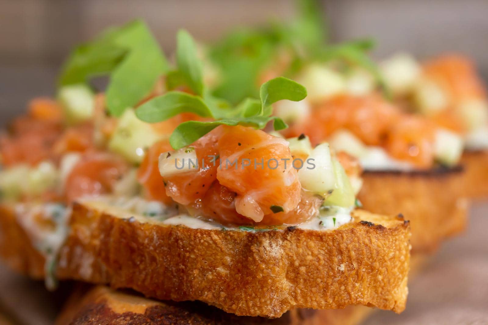 dry aged smoked salmon on the slices of bread and cream cheese sandwiches with cherry tomatoes and rocket salad by Milanchikov