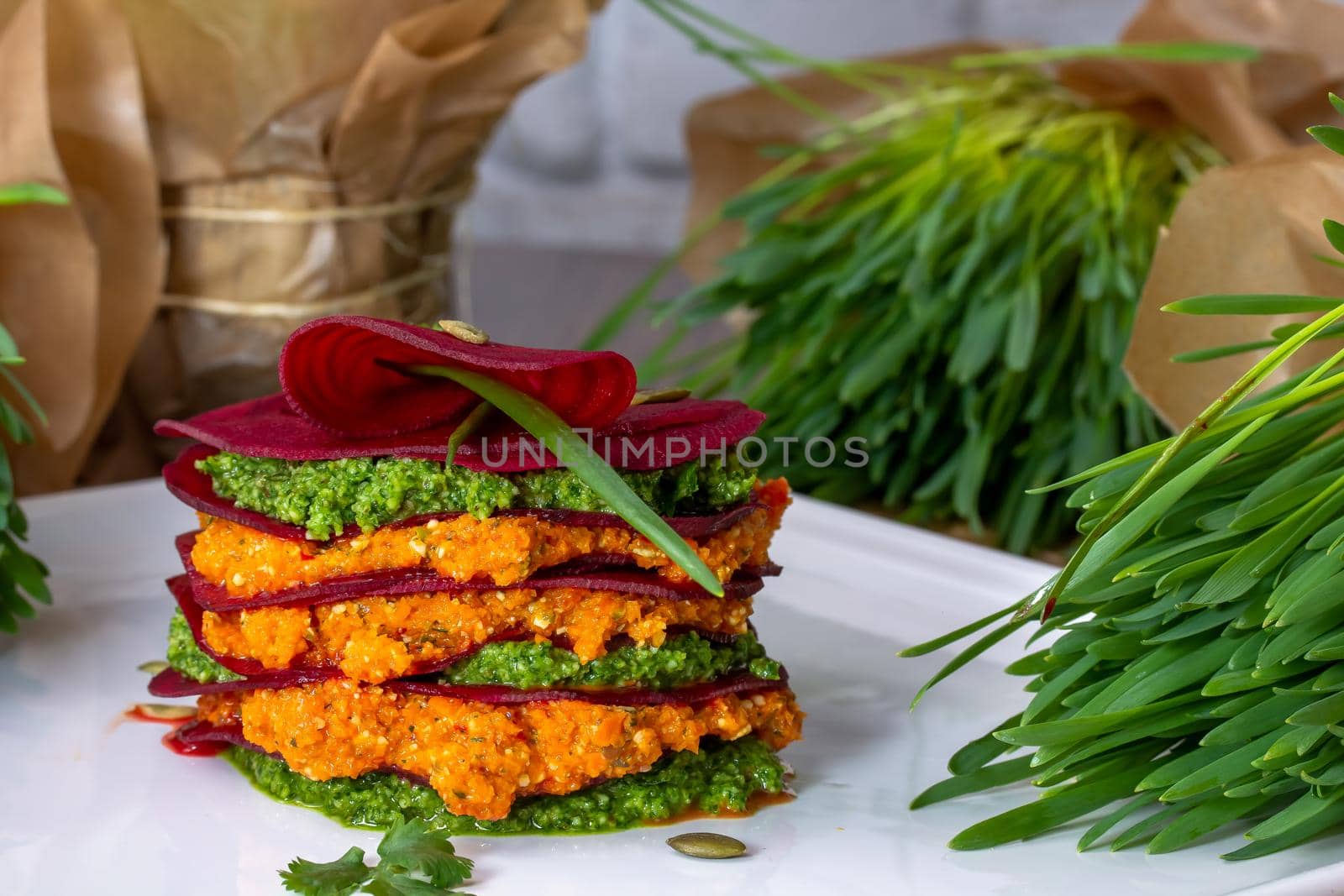 A plate of layer red beetroot napoleon and goat cheese appetizer salad with roasted pistachio and dill leaves, lemon in background. Shape as French mille-feuille a healthy dish and ideal for diet.