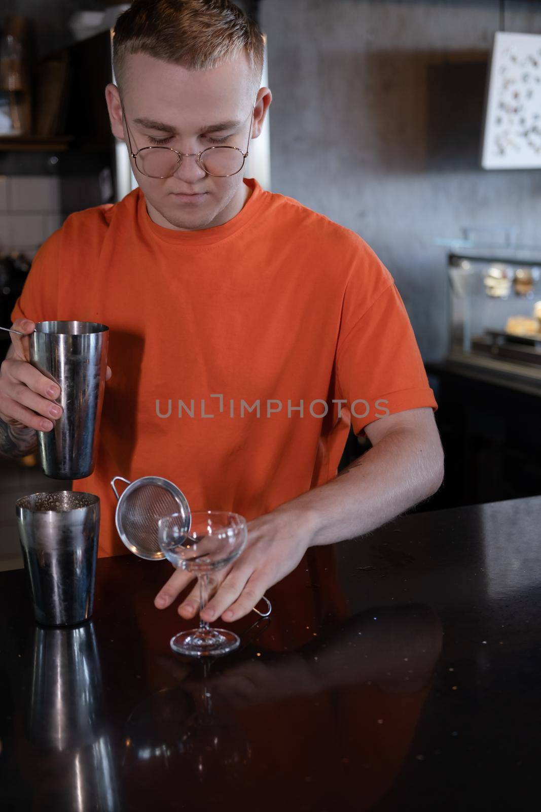 Barman is making cocktail at night club. stylish young man mixing a cocktail in a dark loft cafe. alcohol drink in modern bar. male bartender by oliavesna