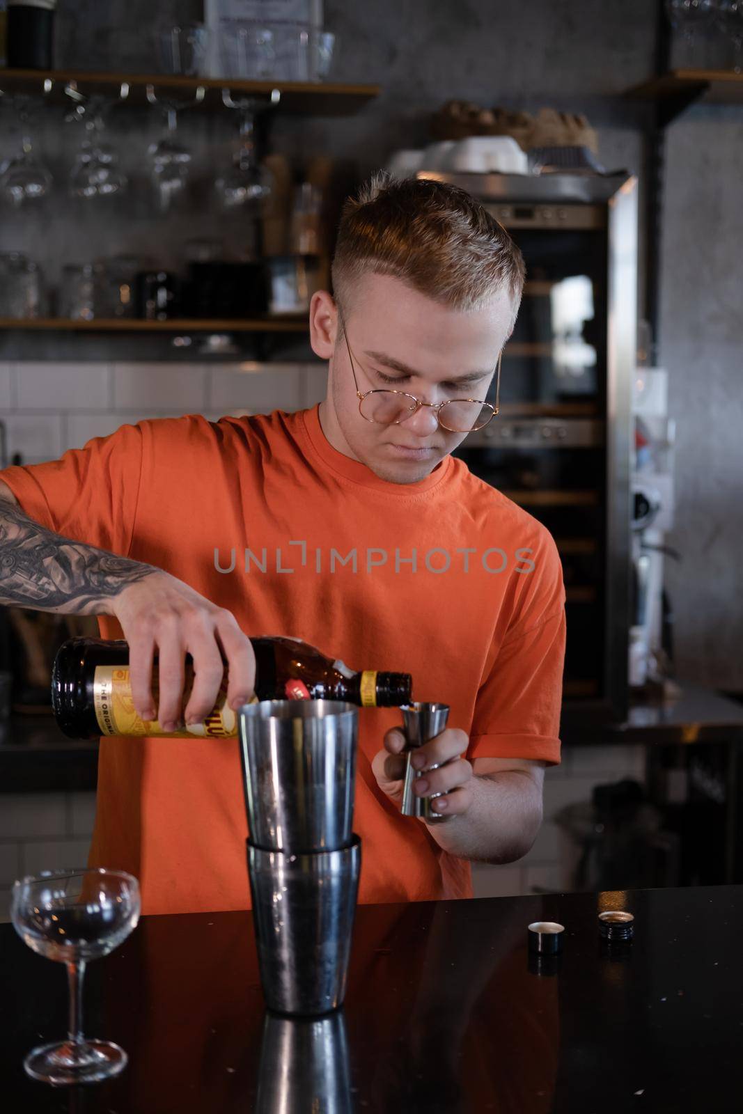 Barman is making cocktail at night club. stylish young man mixing a cocktail in a dark loft cafe. alcohol drink in modern bar. male bartender.