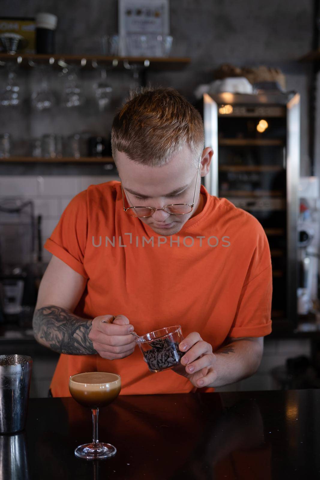 Barman is making cocktail at night club. stylish young man mixing a cocktail in a dark loft cafe. alcohol drink in modern bar. male bartender.