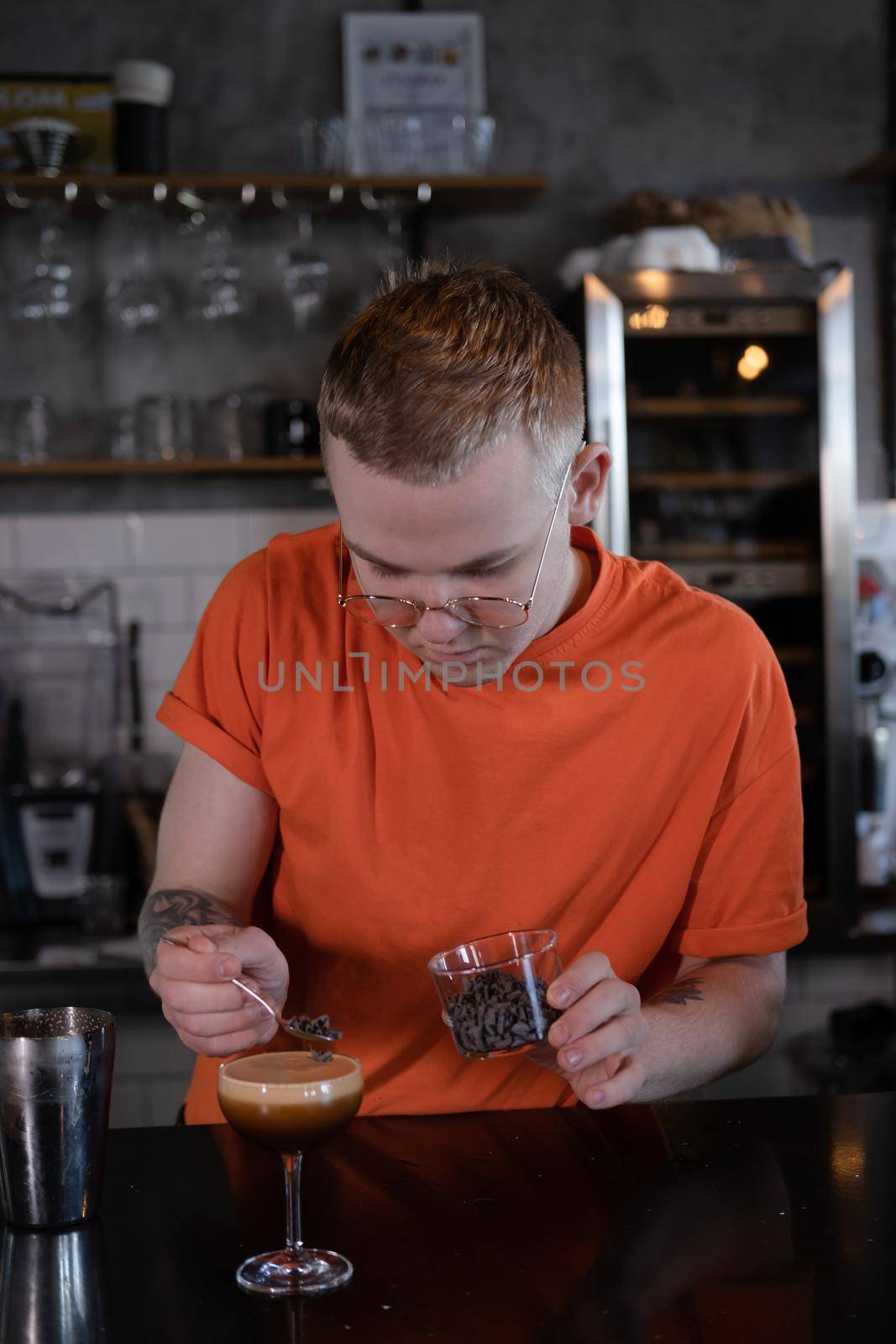 Barman is making cocktail at night club. stylish young man mixing a cocktail in a dark loft cafe. alcohol drink in modern bar. male bartender.