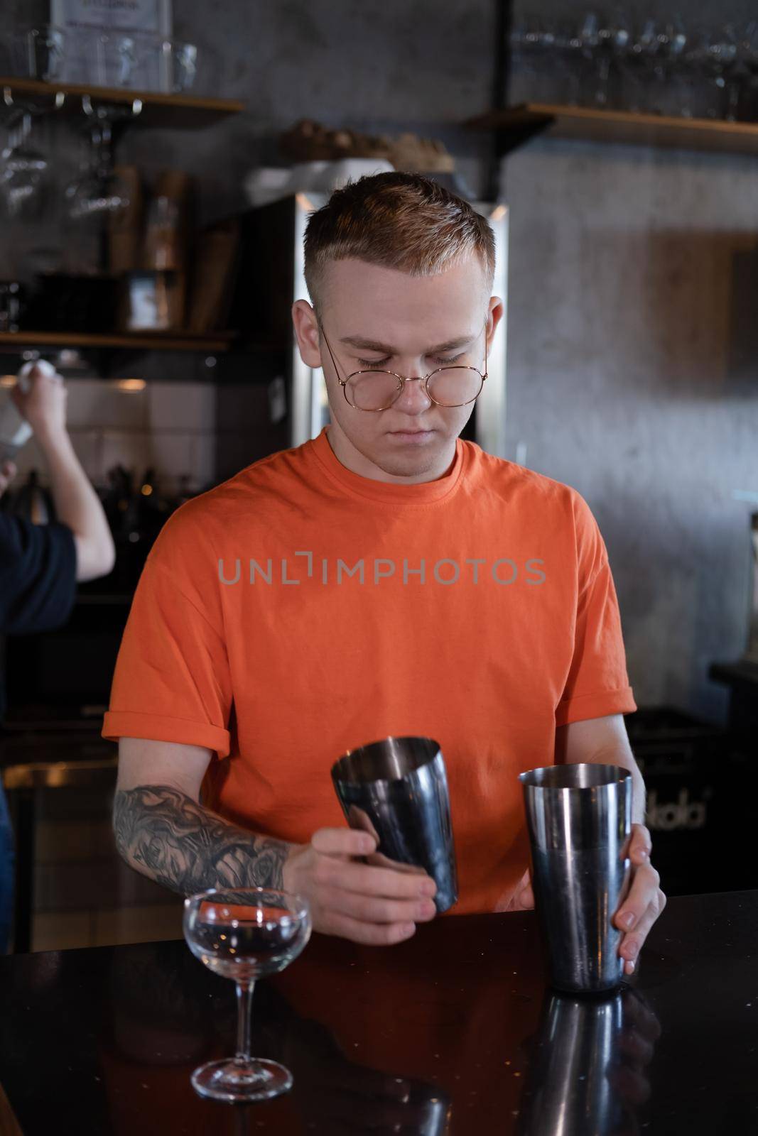 Barman is making cocktail at night club. stylish young man mixing a cocktail in a dark loft cafe. alcohol drink in modern bar. male bartender.