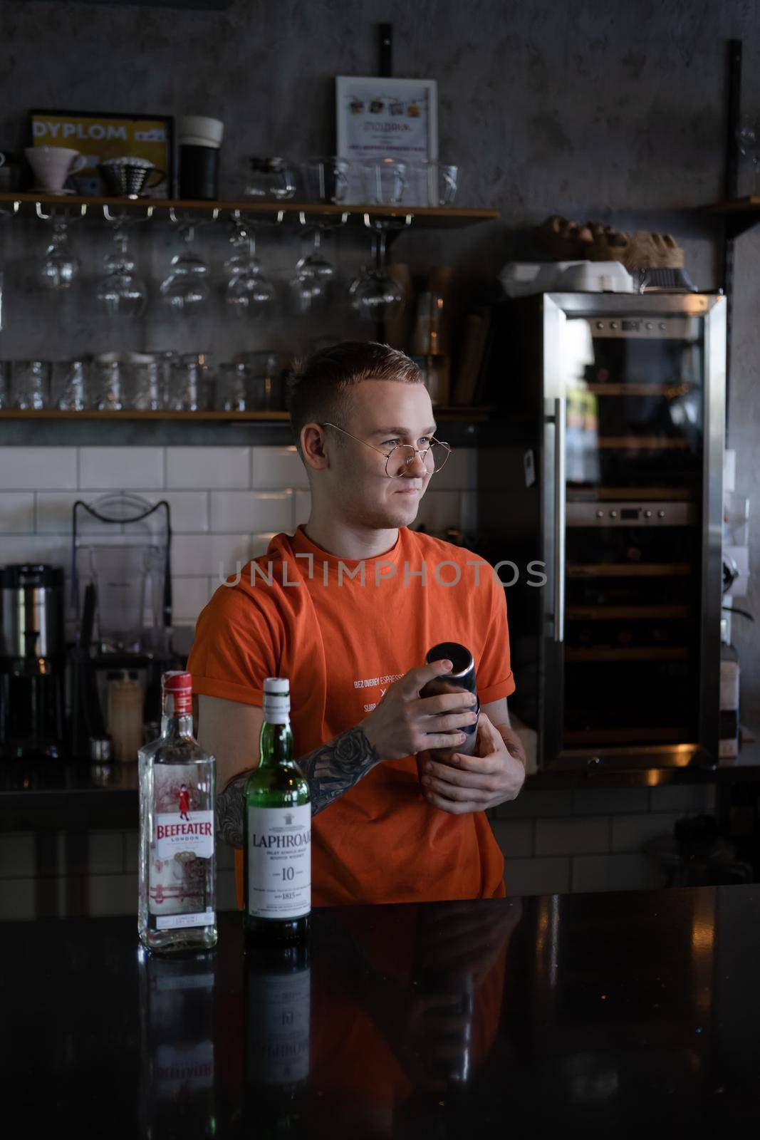 Barman is making cocktail at night club. stylish young man mixing a cocktail in a dark loft cafe. alcohol drink in modern bar. male bartender by oliavesna