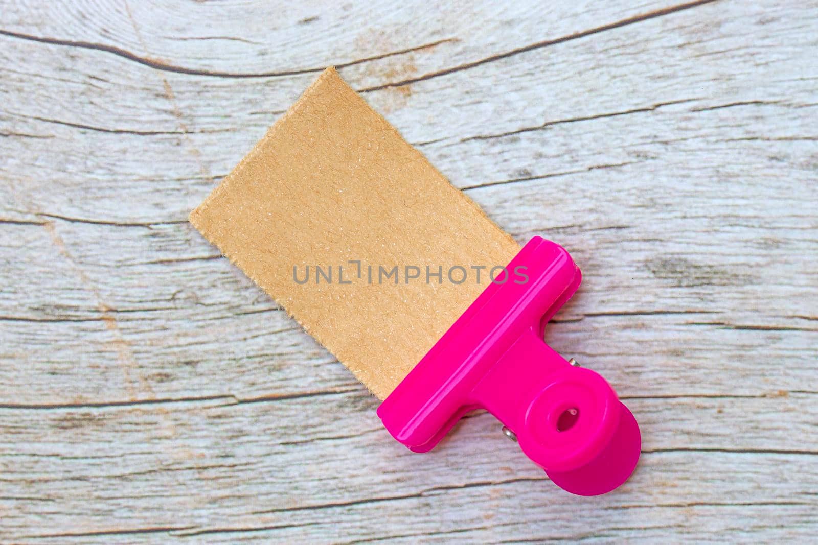 Torn brown paper on wooden surface with paper clip holder. Flat lay with copy space. Directly above.