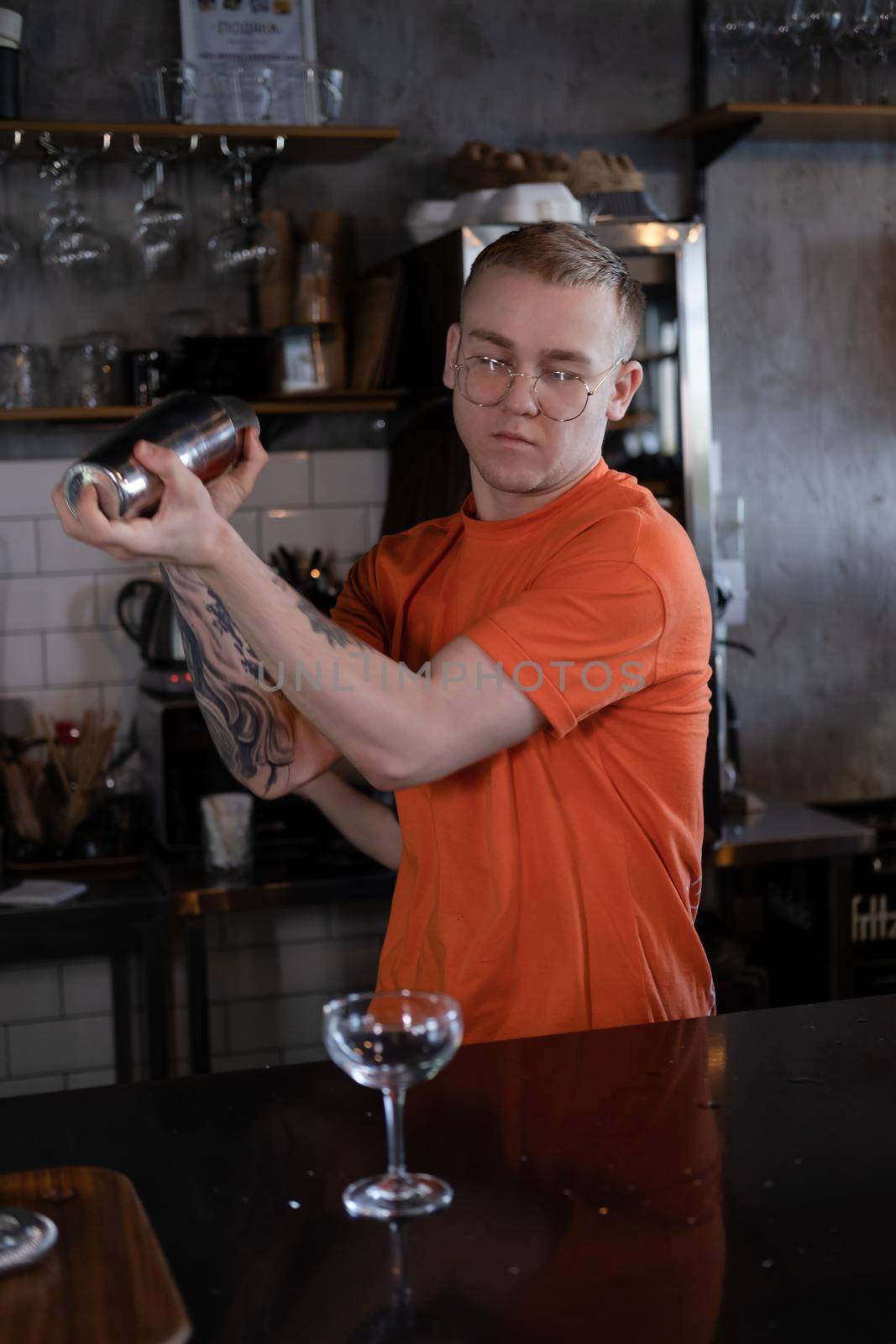 Barman is making cocktail at night club. stylish young man mixing a cocktail in a dark loft cafe. alcohol drink in modern bar. male bartender.