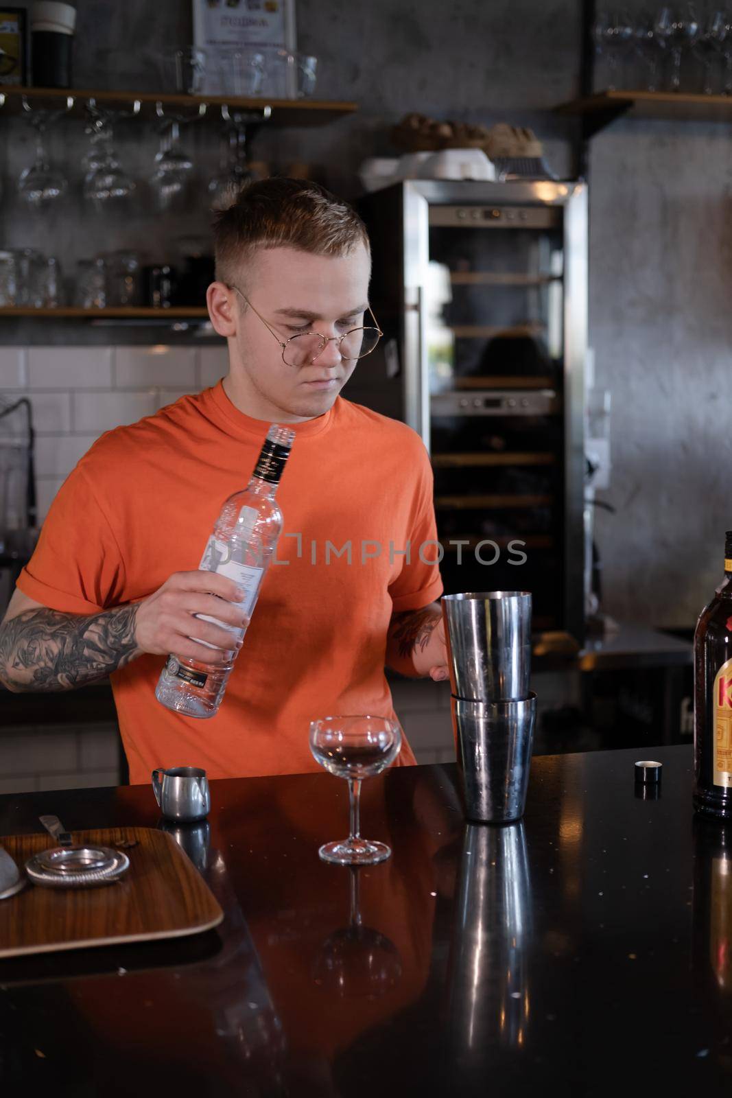 Barman is making cocktail at night club. stylish young man mixing a cocktail in a dark loft cafe. alcohol drink in modern bar. male bartender by oliavesna