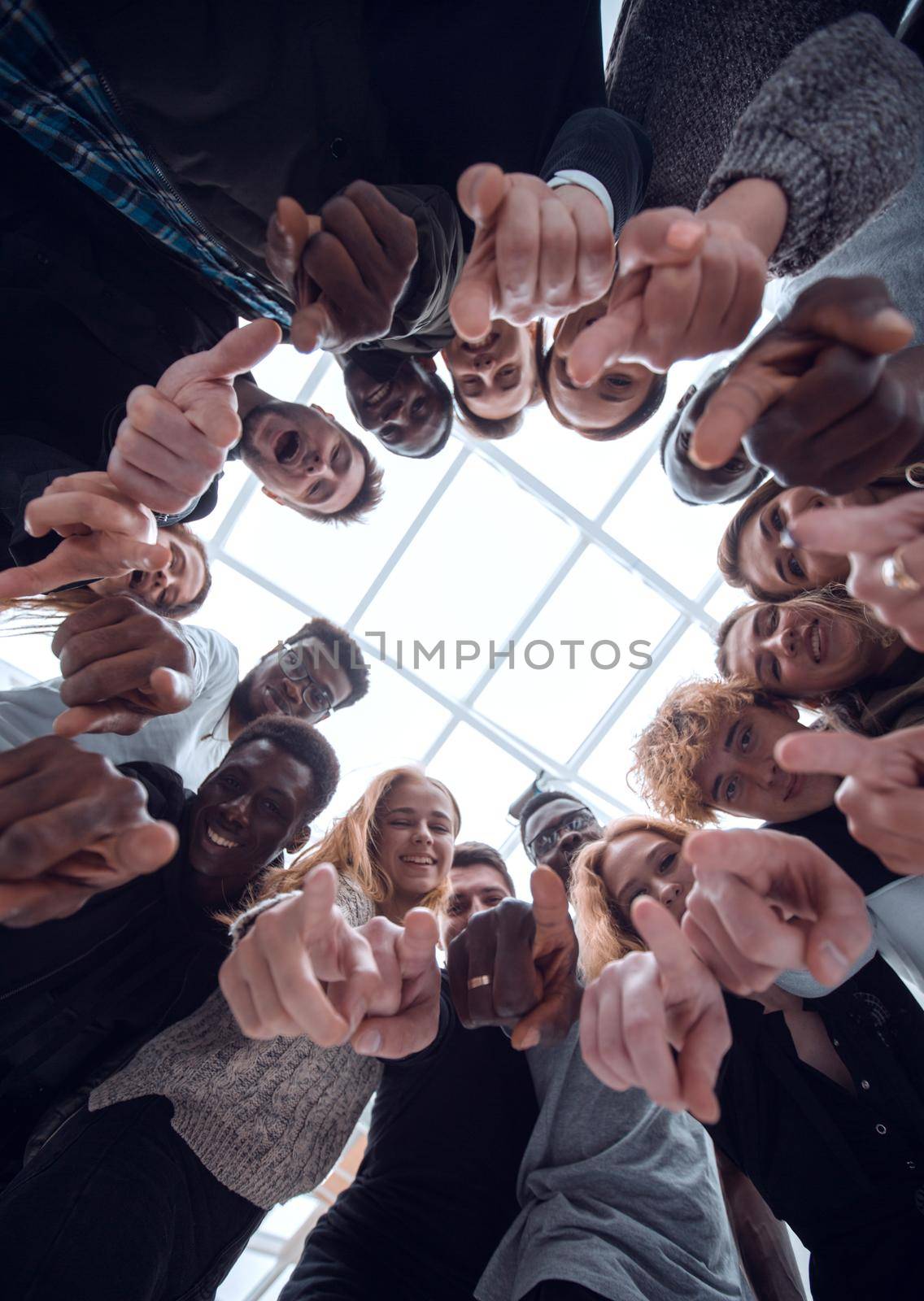 bottom view . group of smiling young people pointing at you . the concept of unity