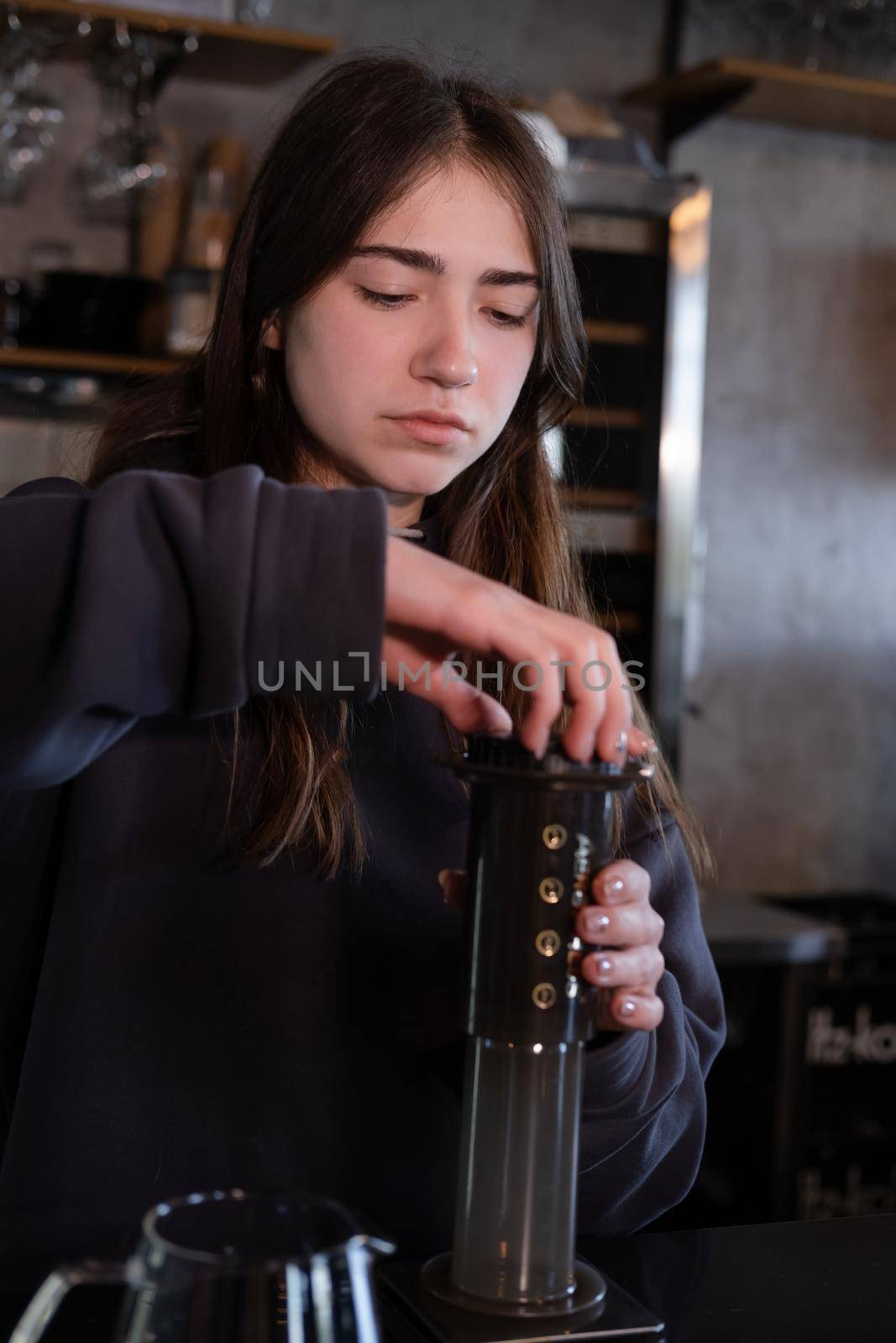 pretty brunette girl making aeropress coffee in modern coffee shop.