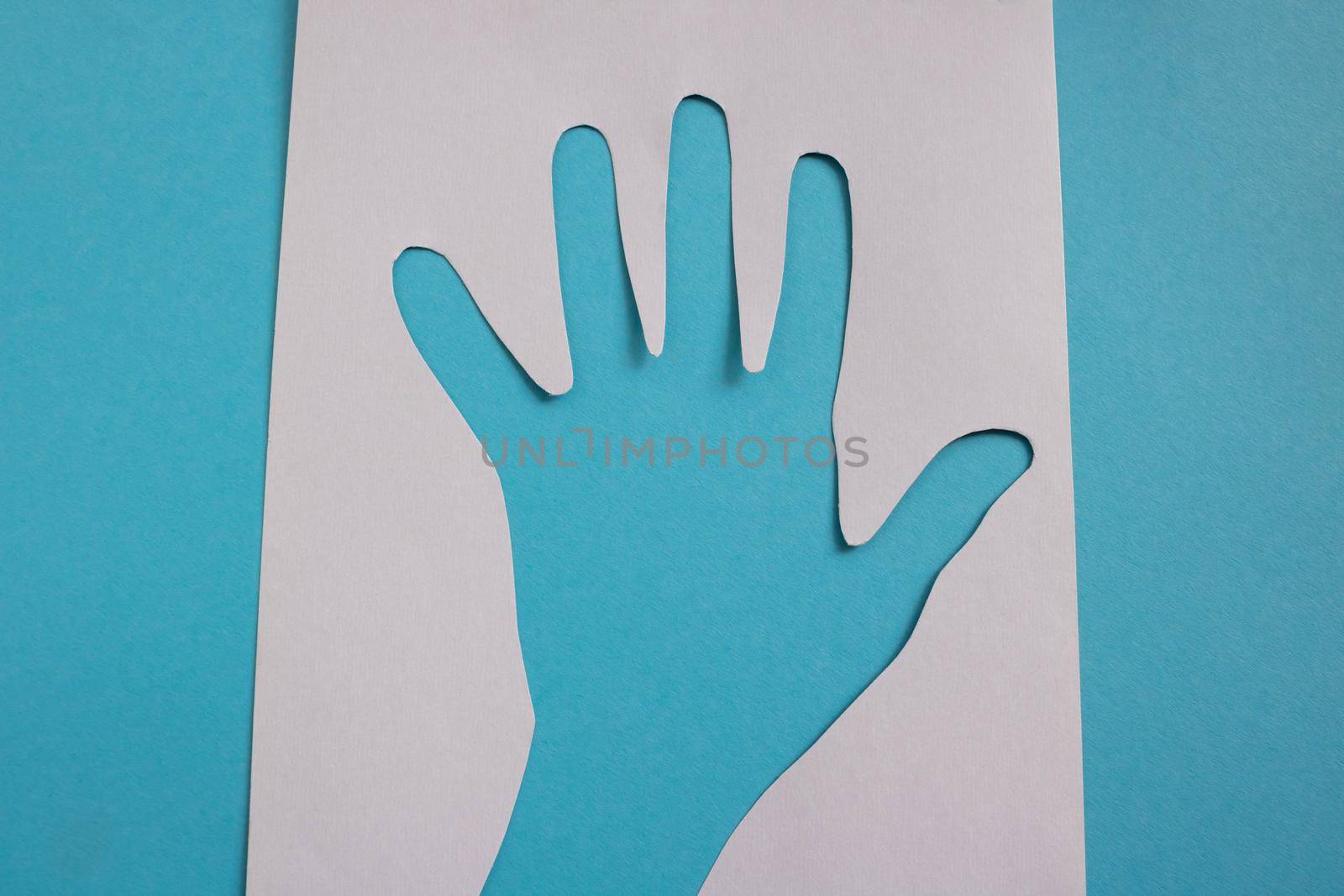 On a blue background, a white paper palm stencil.