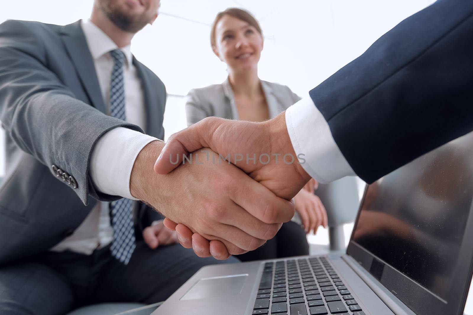 closeup. confident handshake colleagues in front of an open laptop Desk.