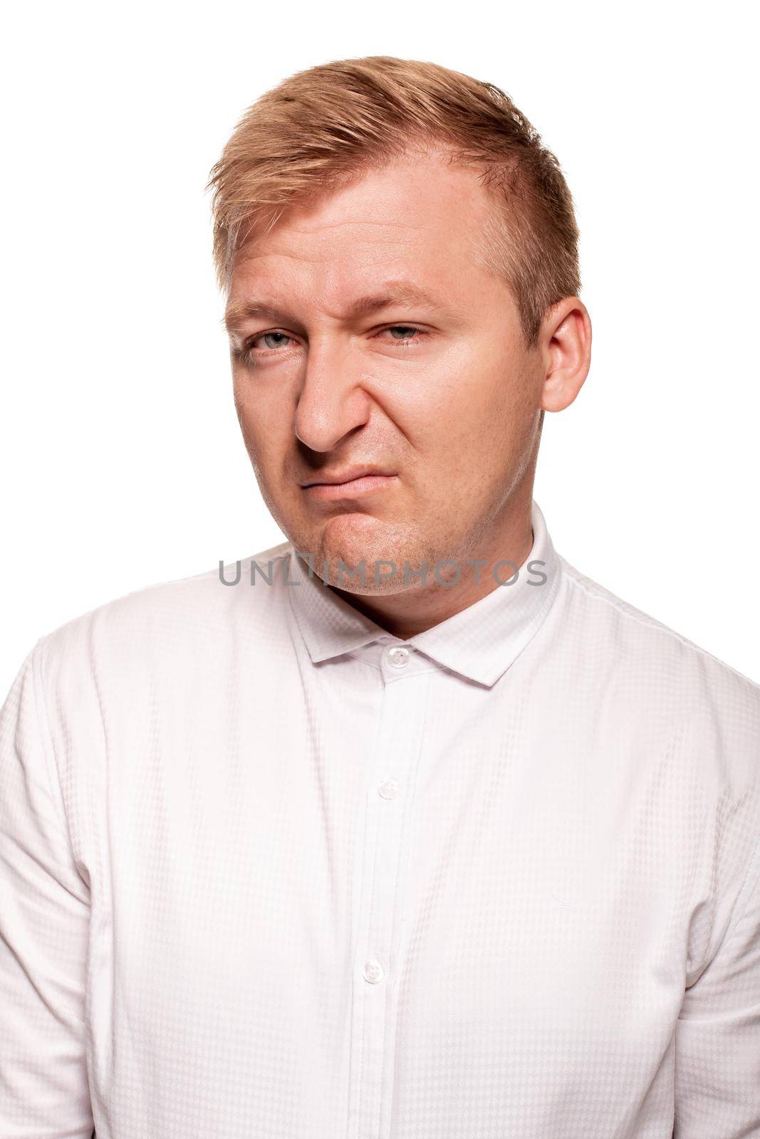 Imposing, young, blond man in a white shirt is grimacing while standing isolated on a white background by nazarovsergey