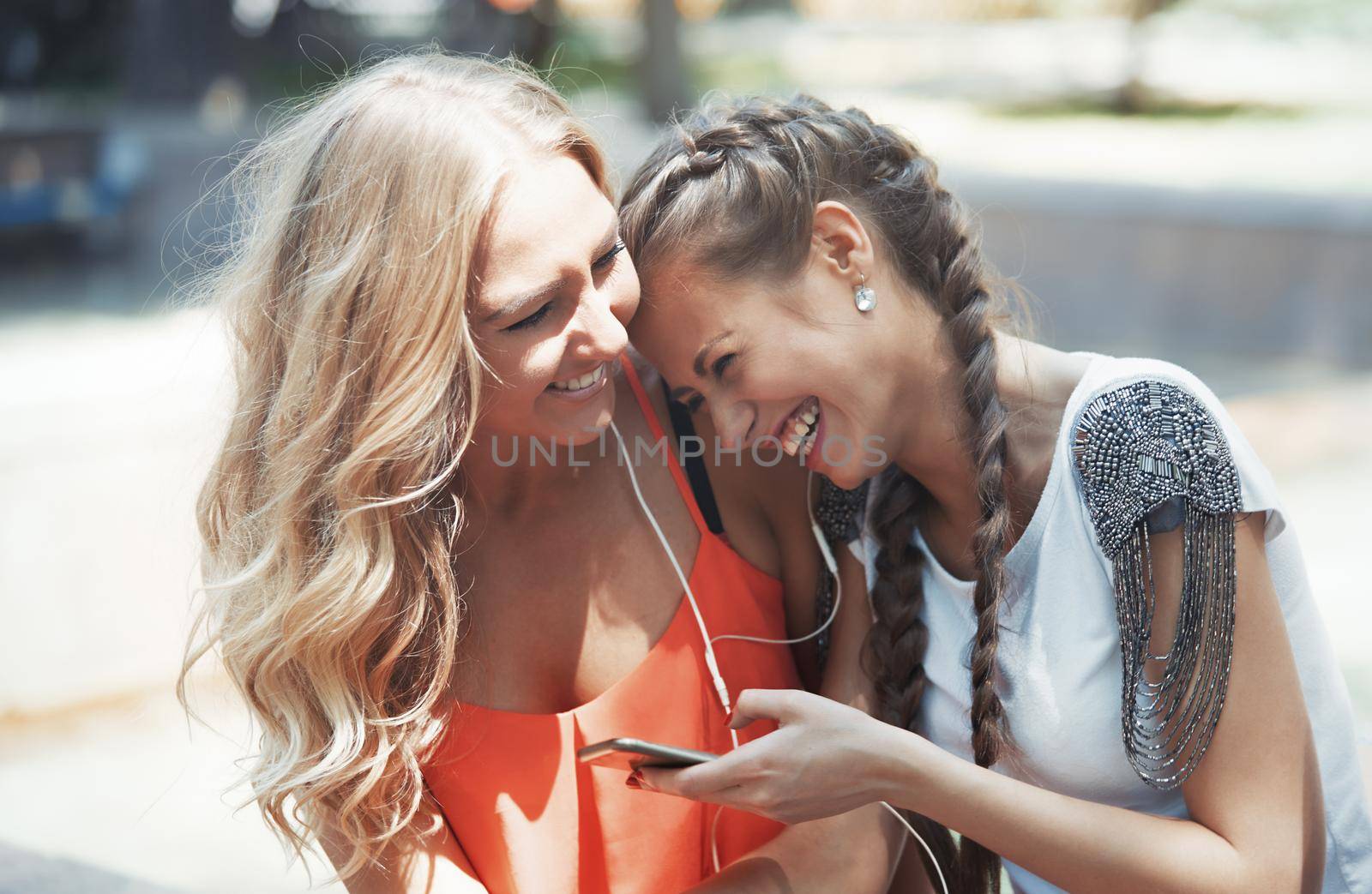 Two girlfriends having fun with smartphone on a city street