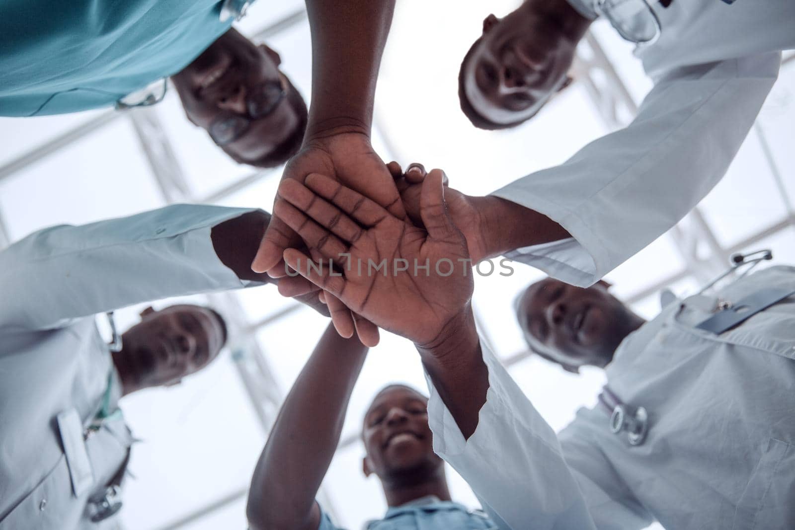 close up. international group of doctors putting their hands together . isolated on white
