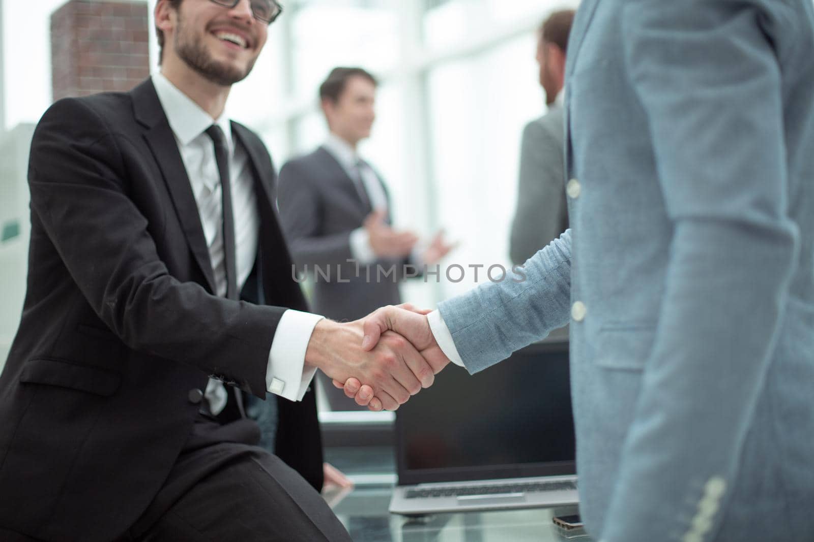 close up. happy young businessman shaking hands with his business partner. concept of cooperation