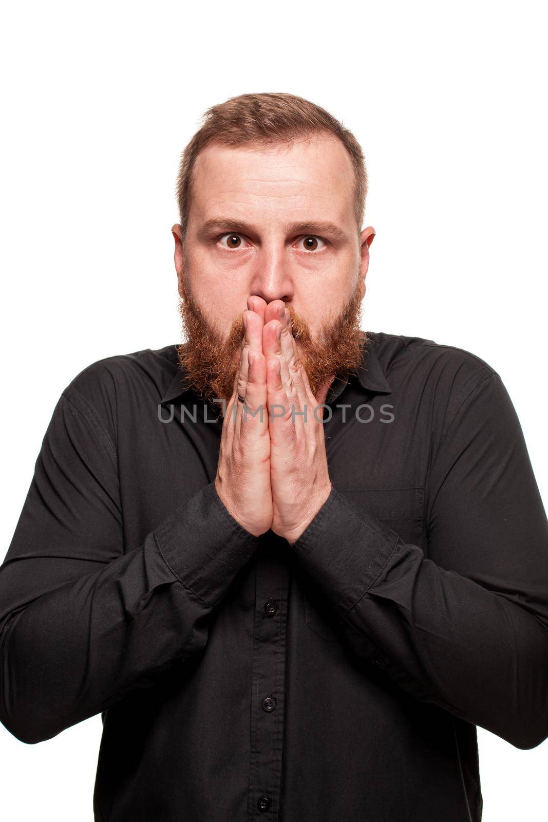 Portrait of a young, chubby, redheaded man with a beard in a black shirt, looking shocked, isolated on a white background