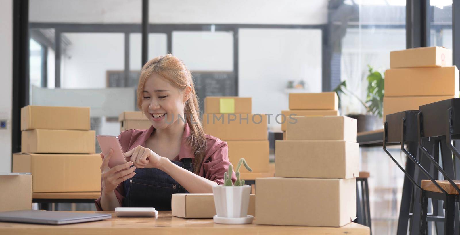 Entrepreneur Woman small business owner taking note of orders from customers with mobile phones. SME entrepreneur or freelance life style concept. by wichayada