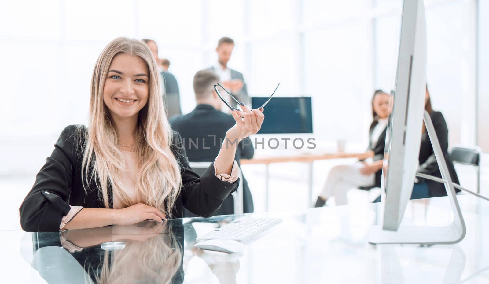 smiling young woman sitting at a Desk in the office by asdf