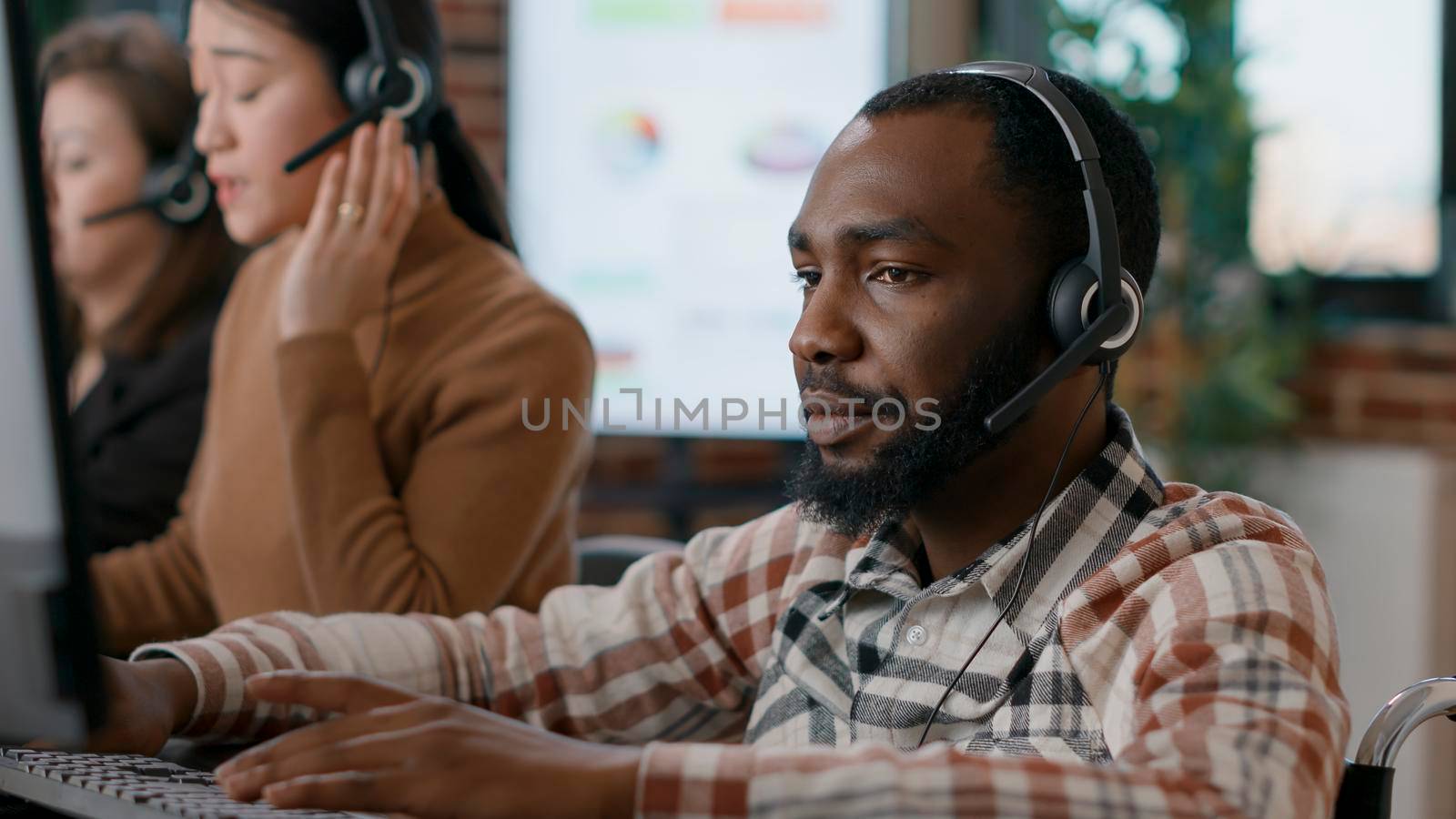 Young man answering telework call at customer service job by DCStudio