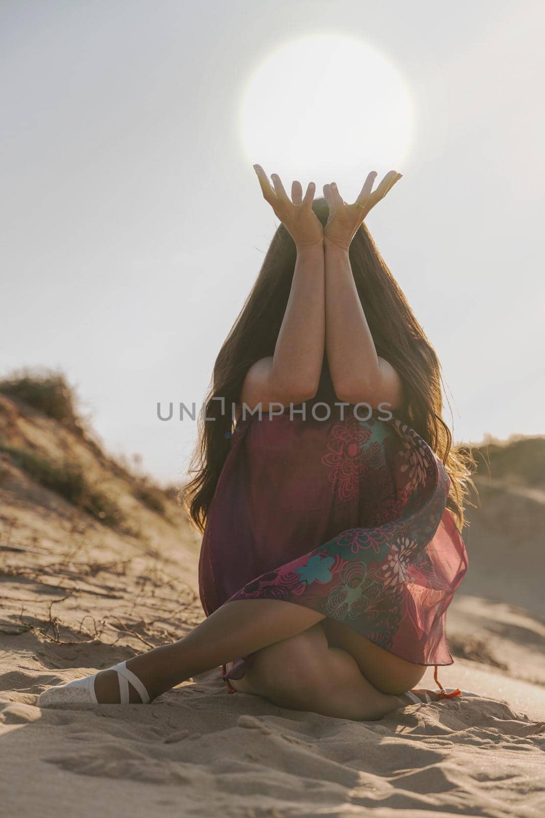 Woman holding arms up in the desert sun in flowing dress by Mareno