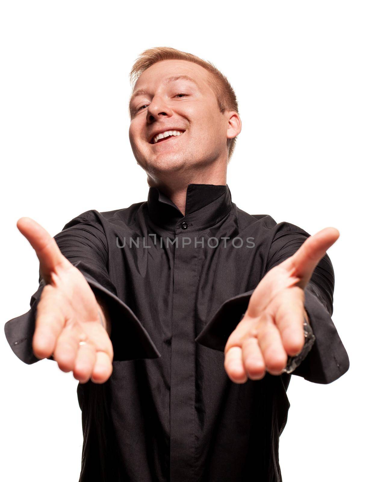 Young blond man in a black shirt, watches and bracelet is making faces and gesticulating at the camera, isolated on a white background