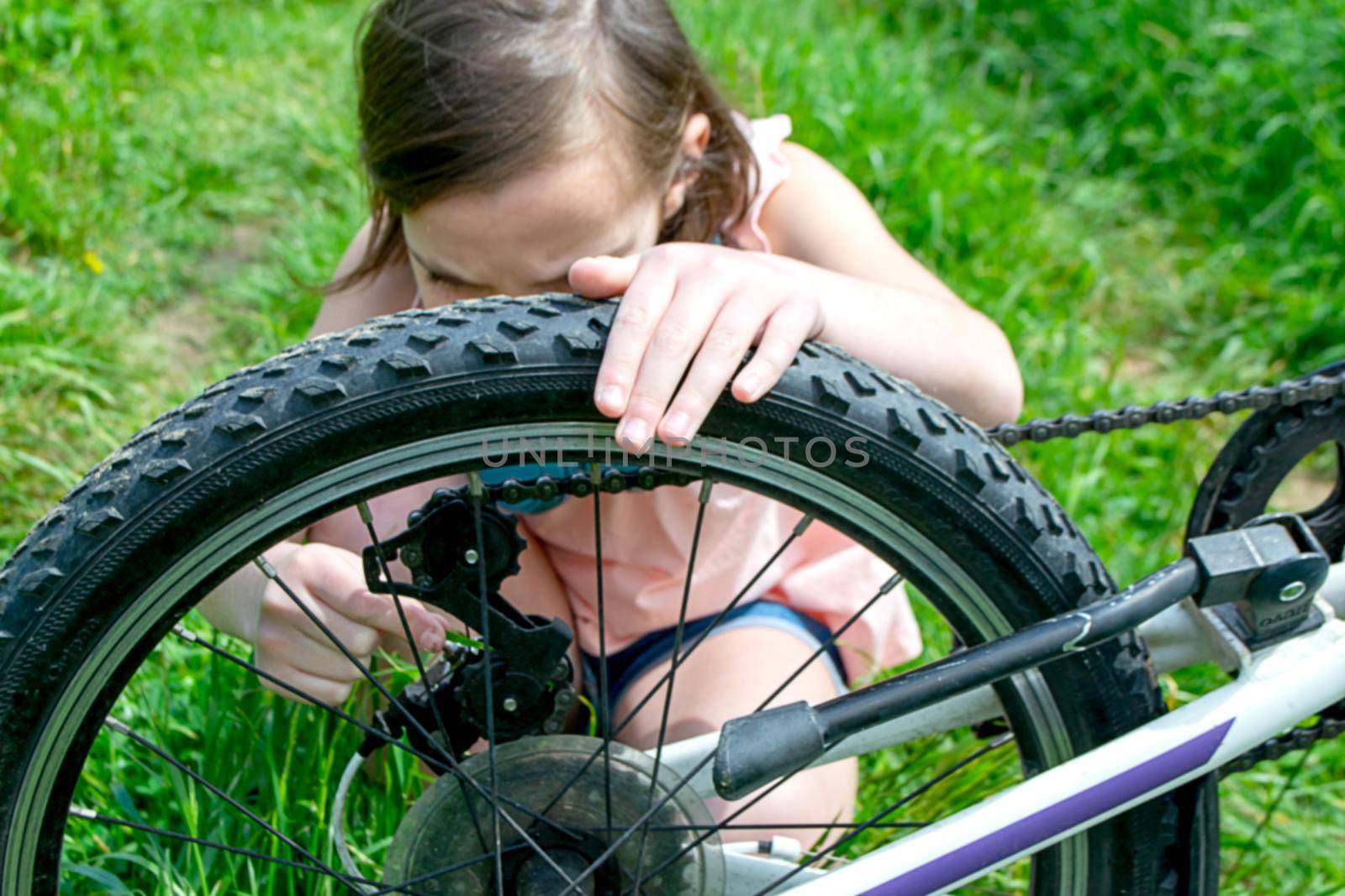 a child girl has damaged a bicycle wheel and is making repairs photo without processing. High quality photo
