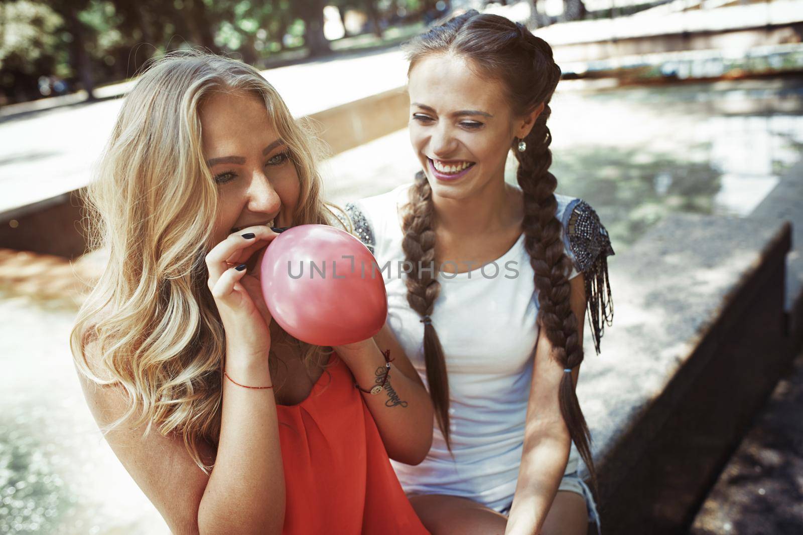 Two girlfriends having fun and blowing balloons