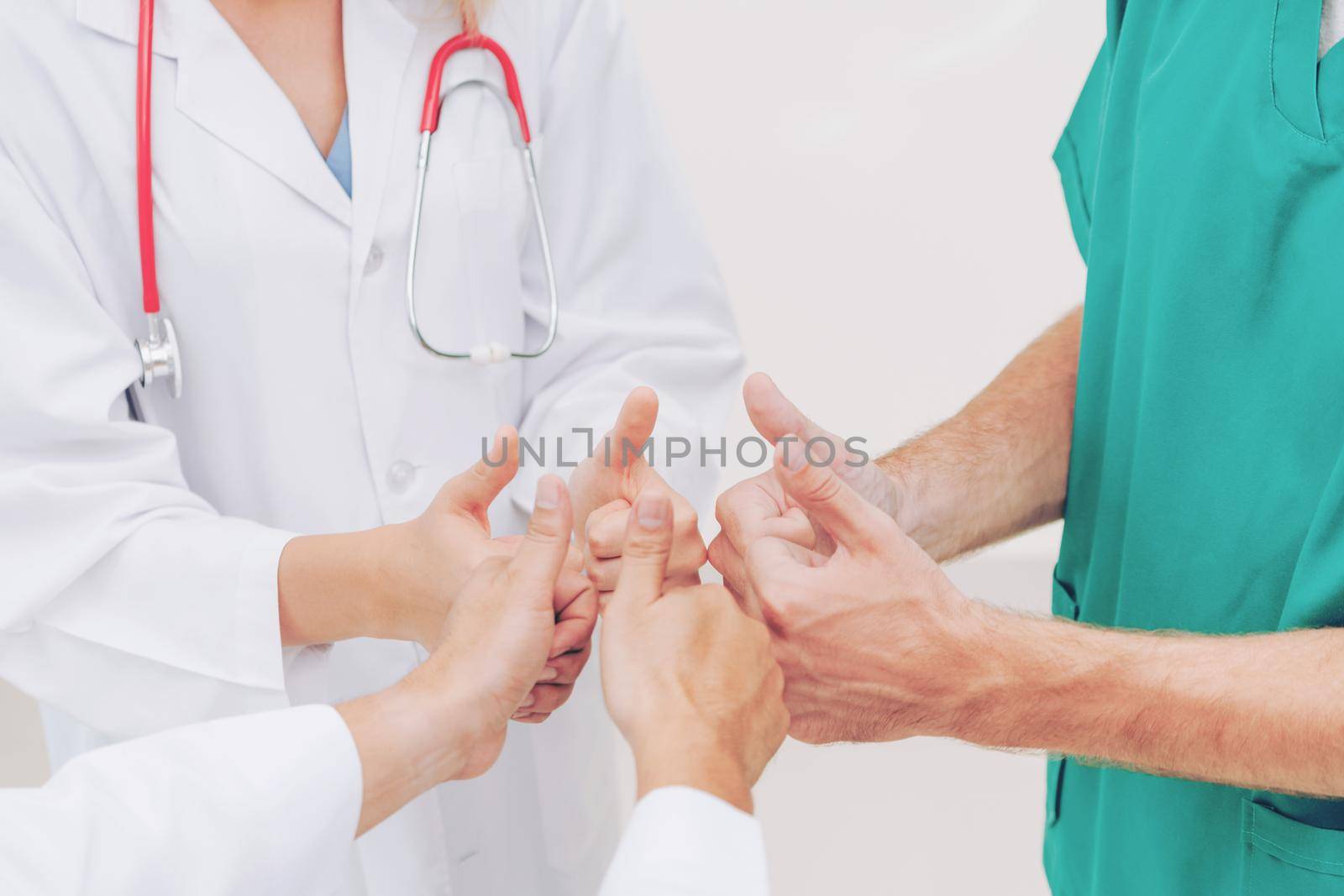 Doctor, surgeon and nurse join hands together. by biancoblue