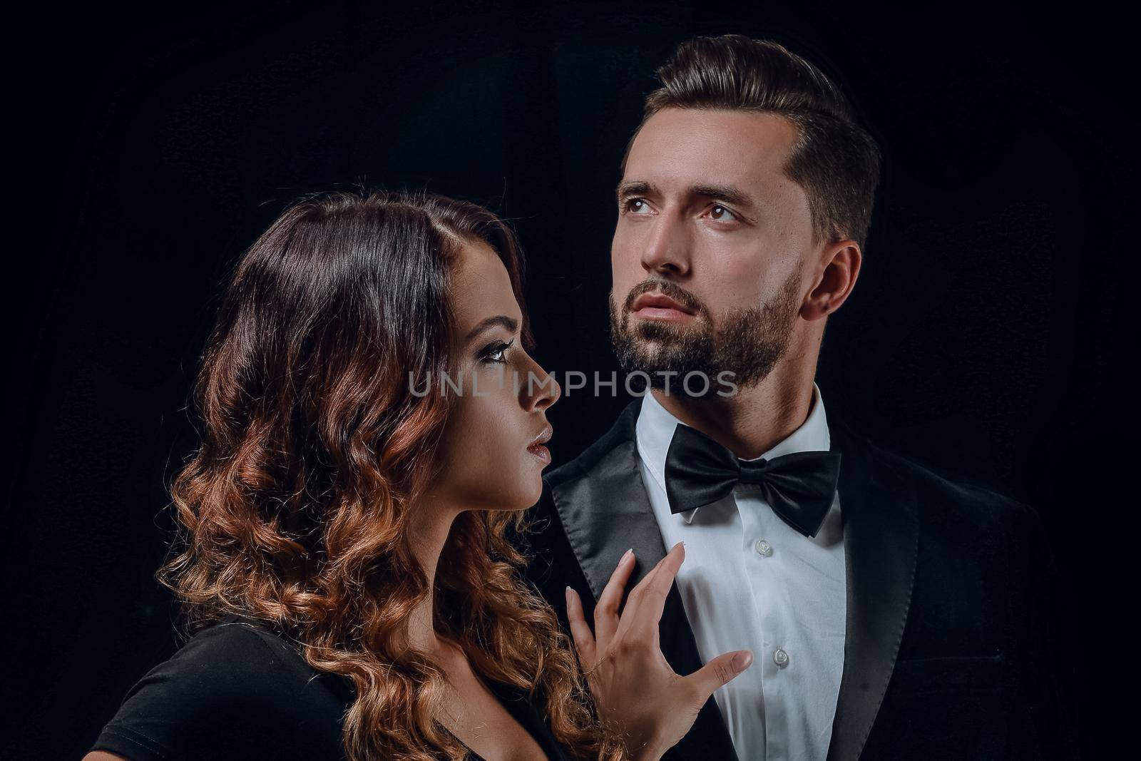 Portrait of a beautiful young couple in love posing at studio over dark background.