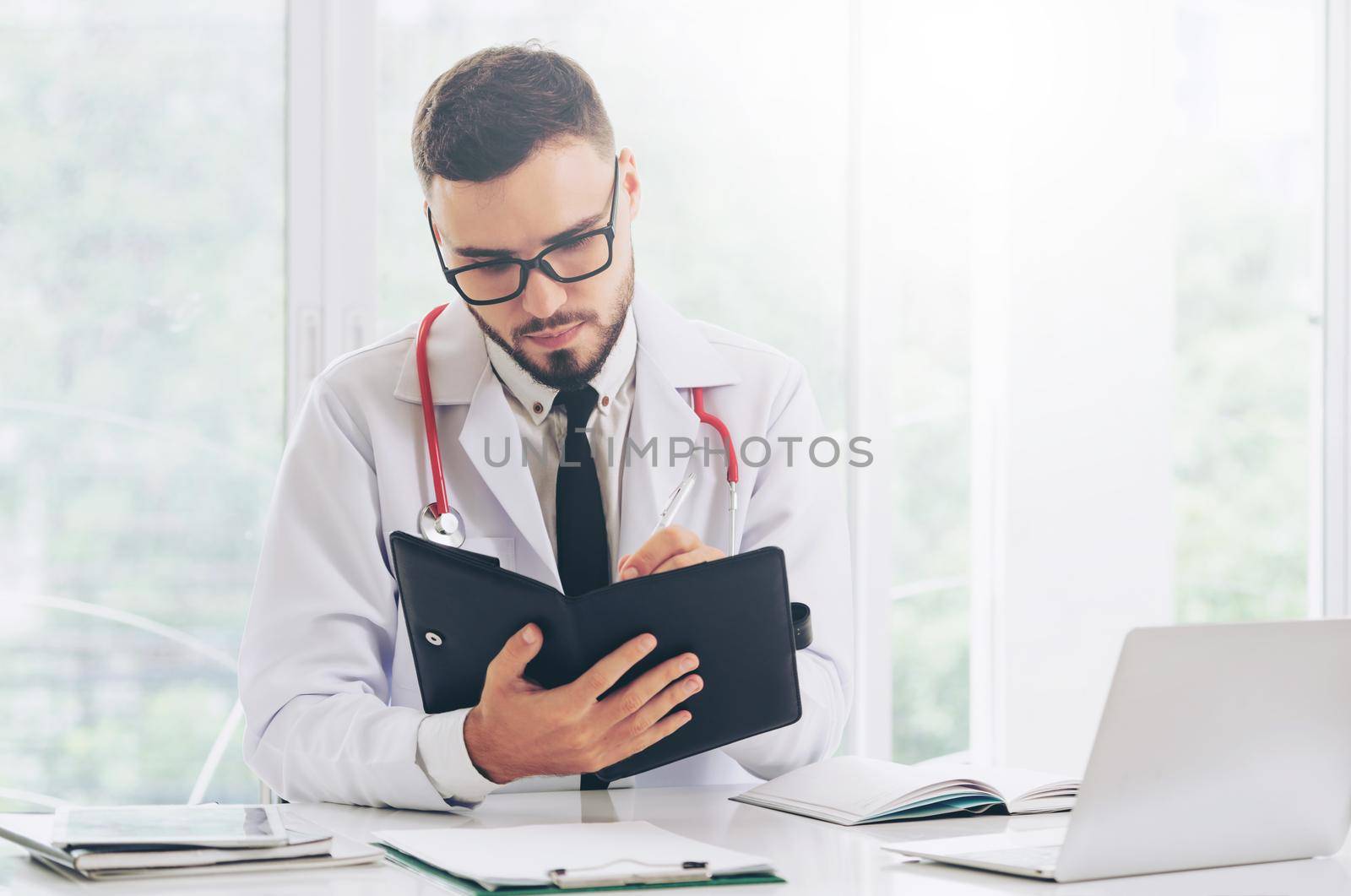Doctor reading while writing note on a book at office in the hospital. Medical and healthcare concept.