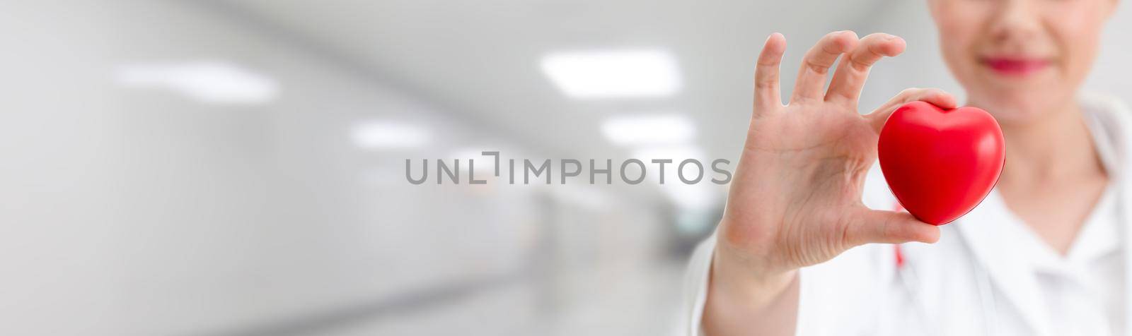 Doctor holding a red heart at hospital office. Medical health care and doctor staff service concept.