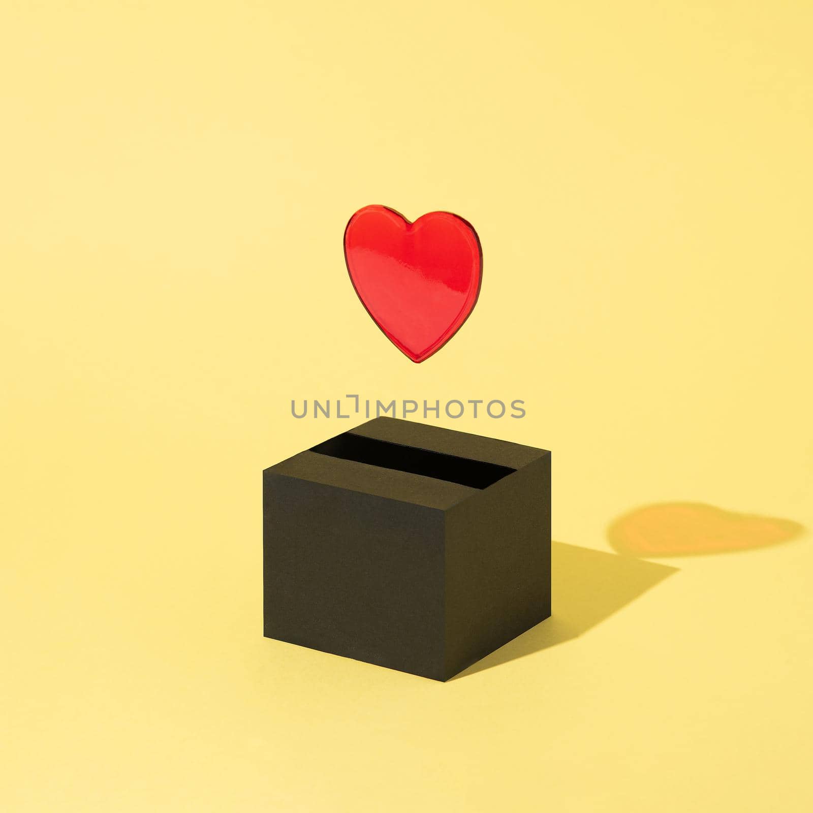 a red heart comes out of a black box and floats on a yellow background. Valentine's Day. by Nemo_Family