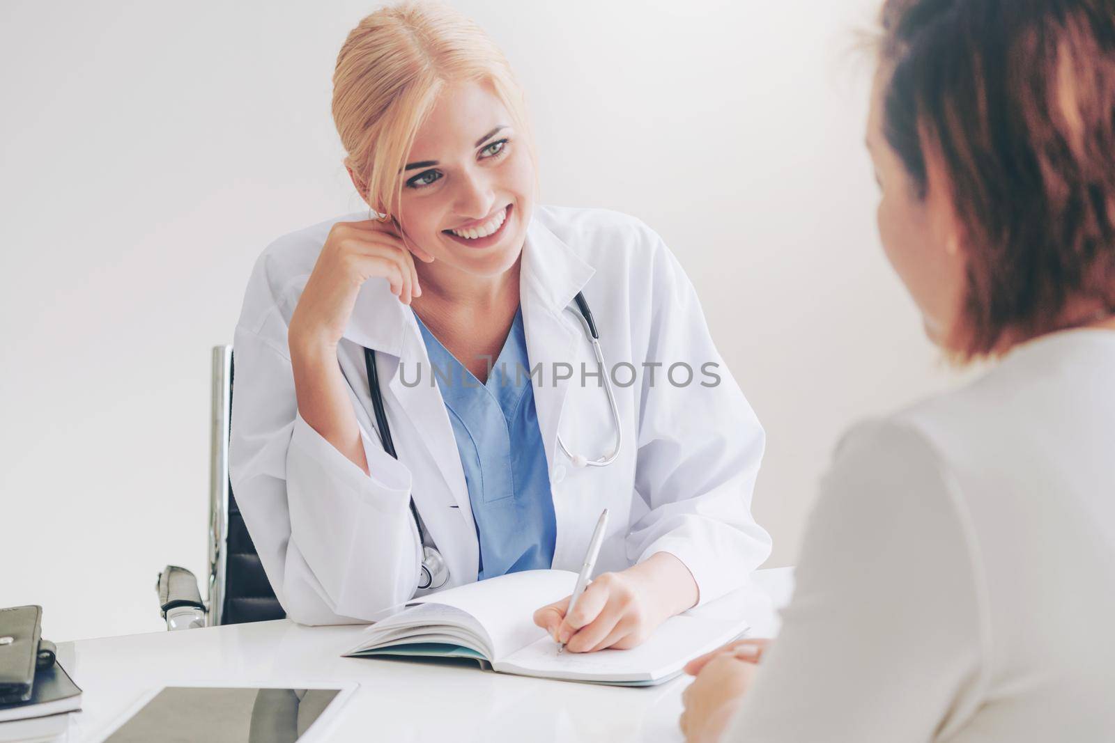 Woman doctor is talking and examining female patient in hospital office. Healthcare and medical service.