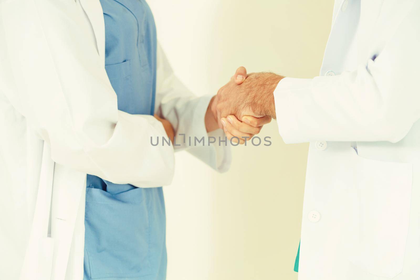 GP doctor shakes hand with surgical doctor. by biancoblue