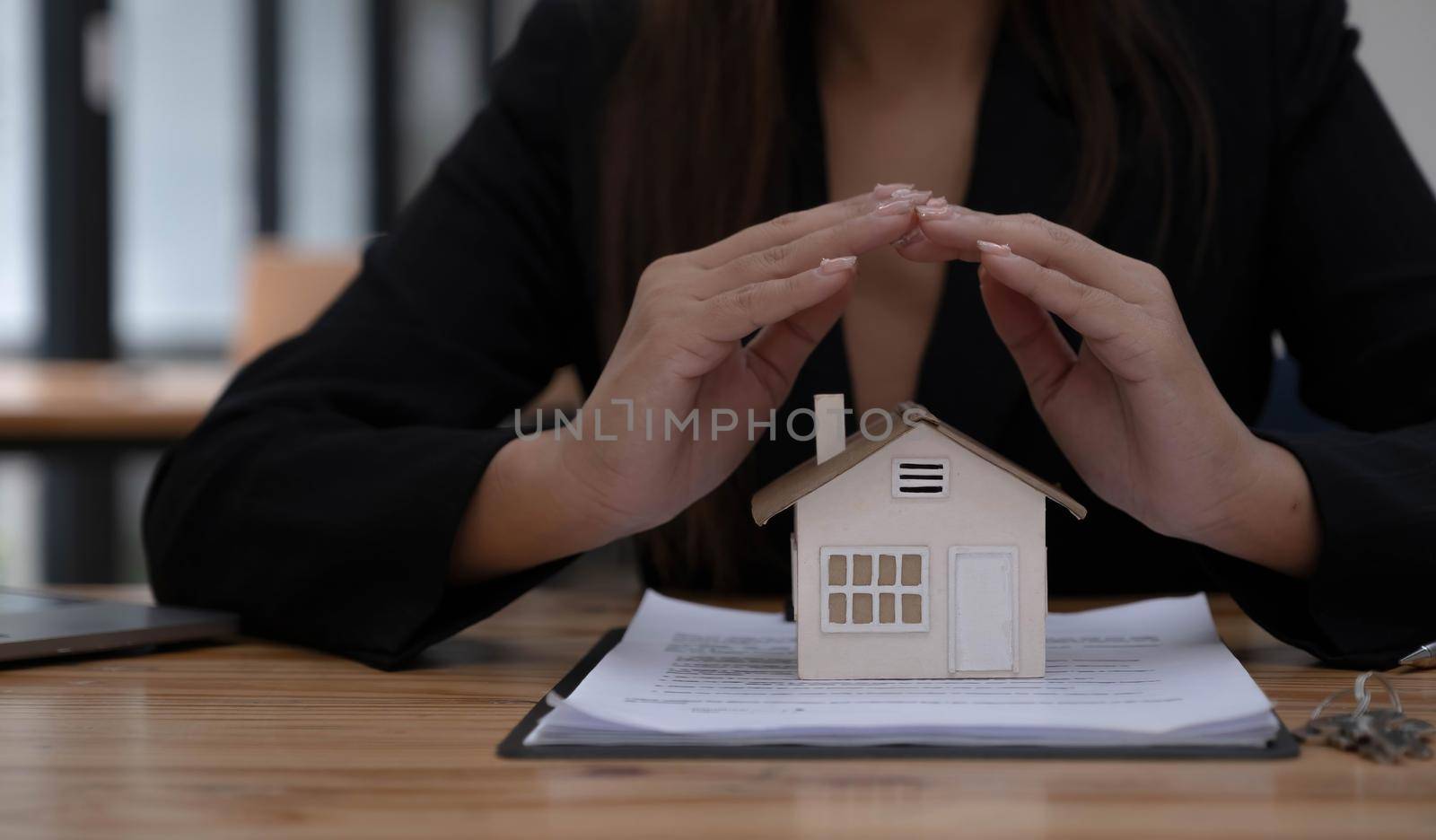 Property insurance and security concept. Protecting gesture of man and symbol of the house. Wide banner composition with office in background. by wichayada