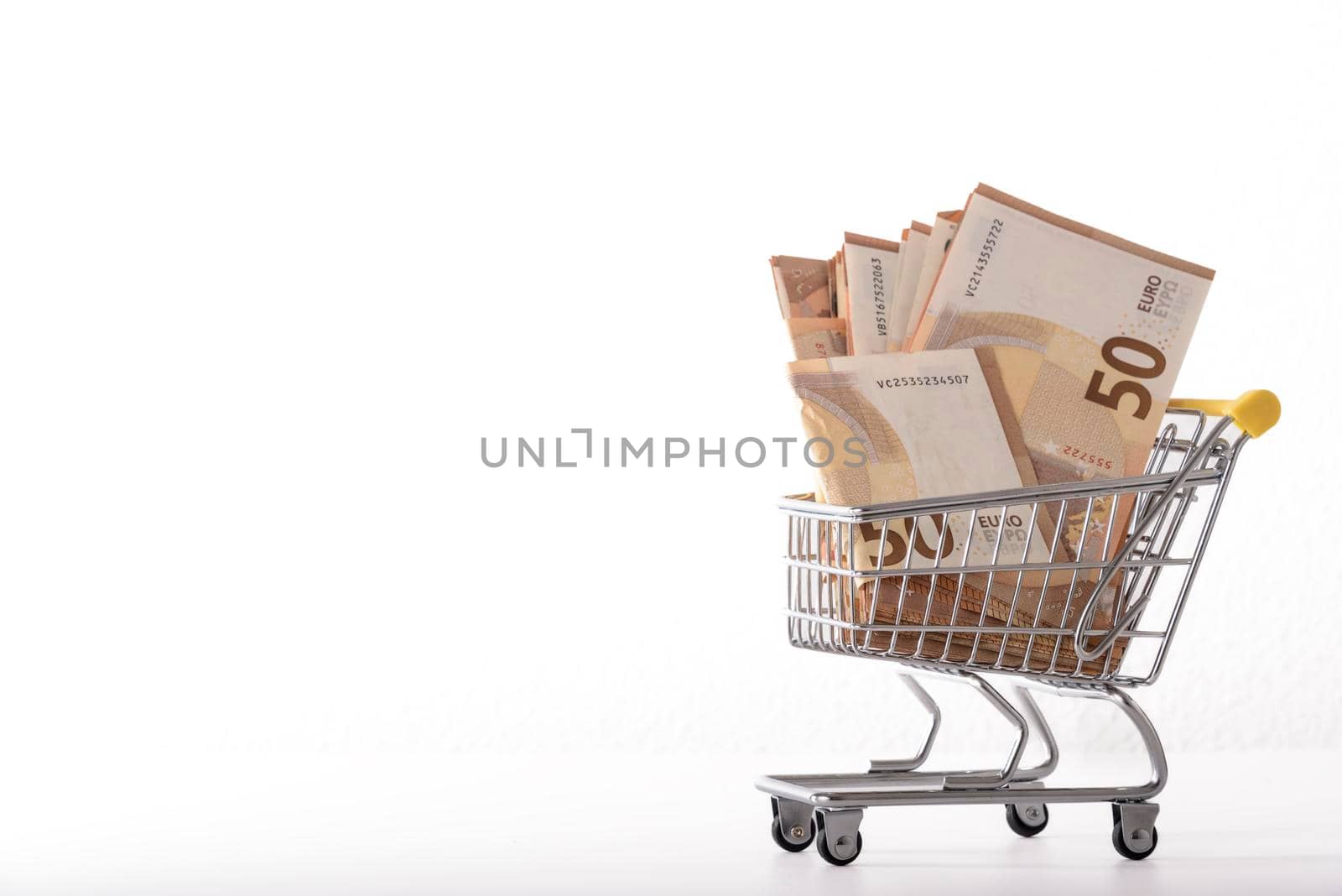 Toy supermarket cart or shopping trolley with money isolated on white background close-up. by jbruiz78