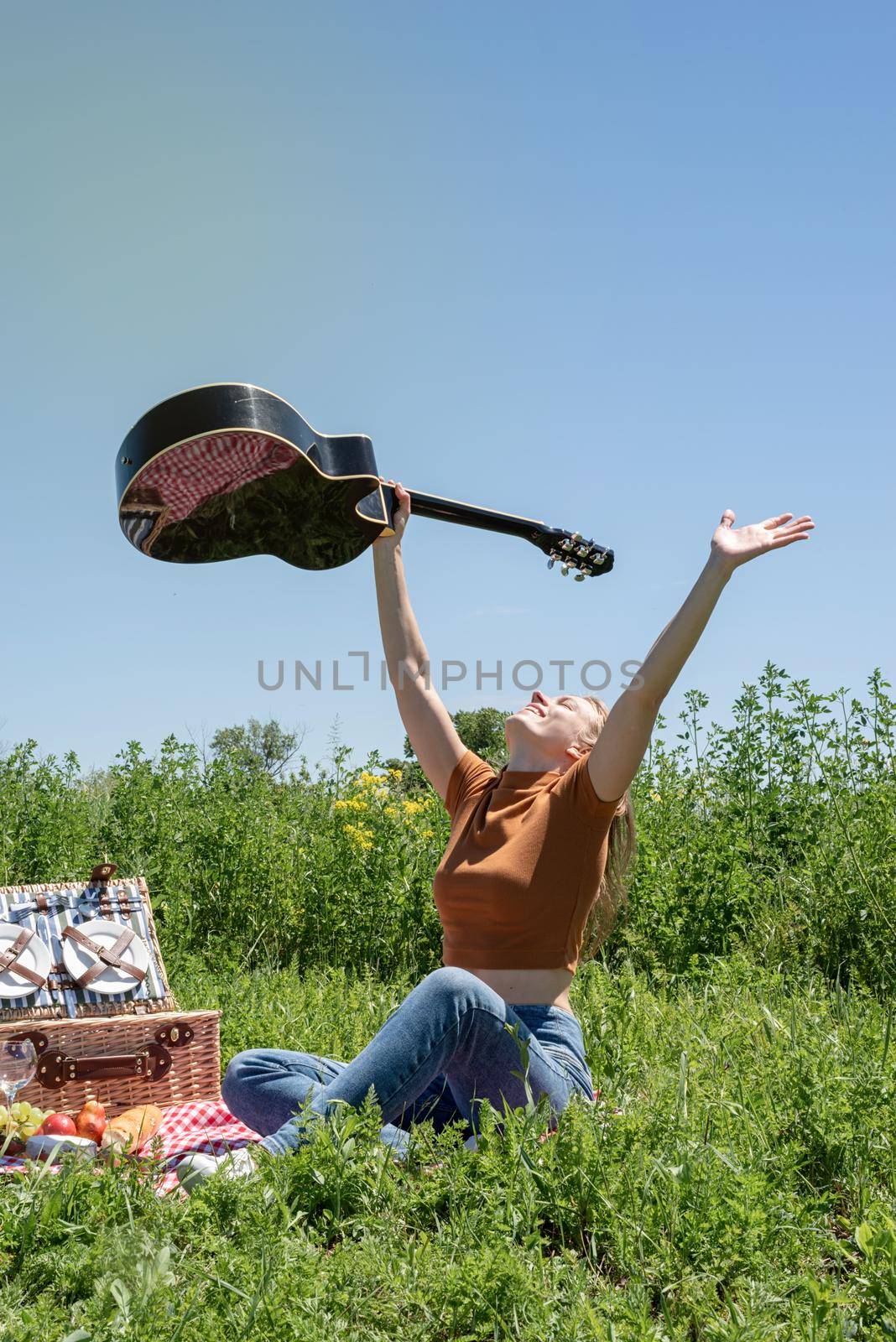 Young woman playing guitar on a picnic by Desperada