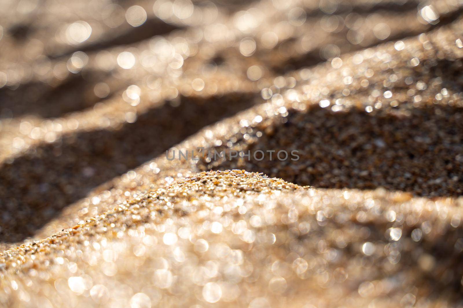 Golden sand on the coast at sunset with bokeh.