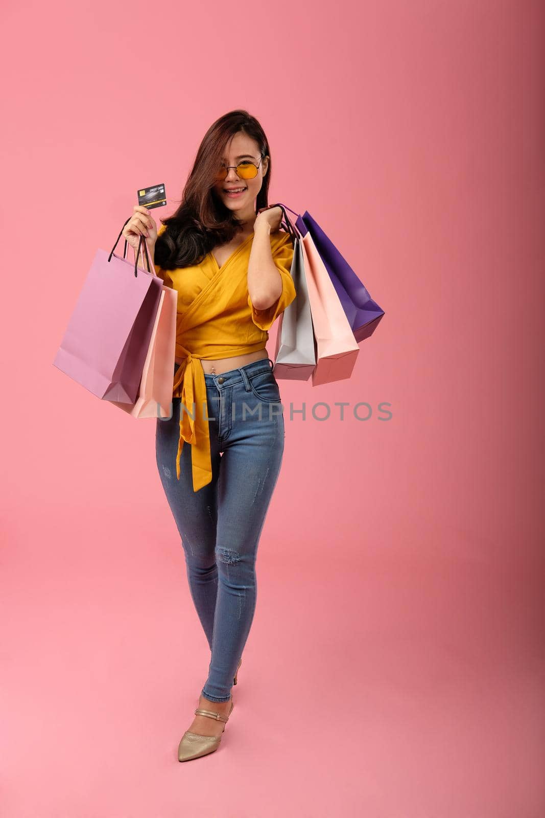 woman holding credit card & shopping bags. consumerism shopaholic lifestyle studio shot