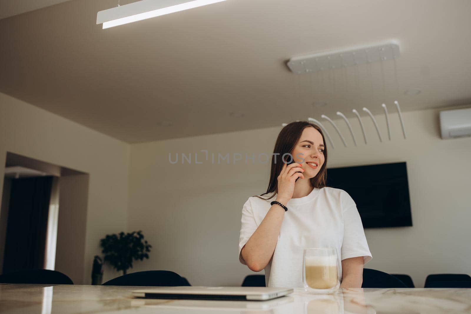 Happy Woman Talking On Mobile Phone While Cooking In Kitchen.