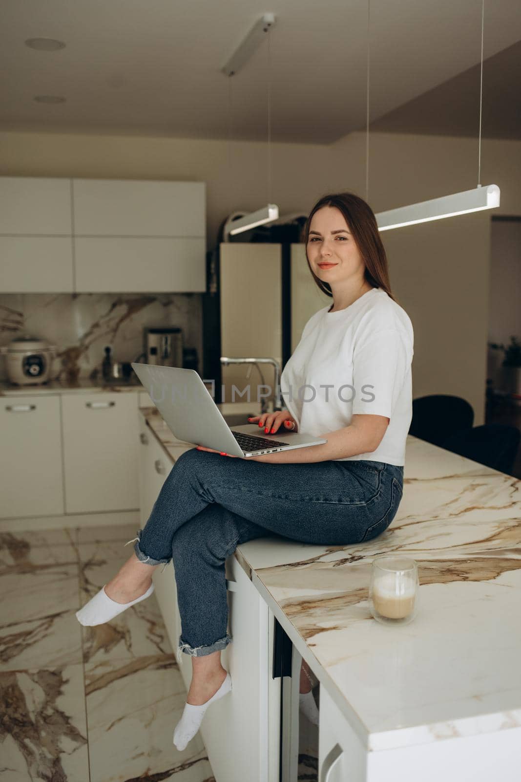 Young woman working from home office. Freelancer using laptop and the Internet for shopping online. Happy girl smiling. Workplace in cozy kitchen. Successful female business. Lifestyle moment