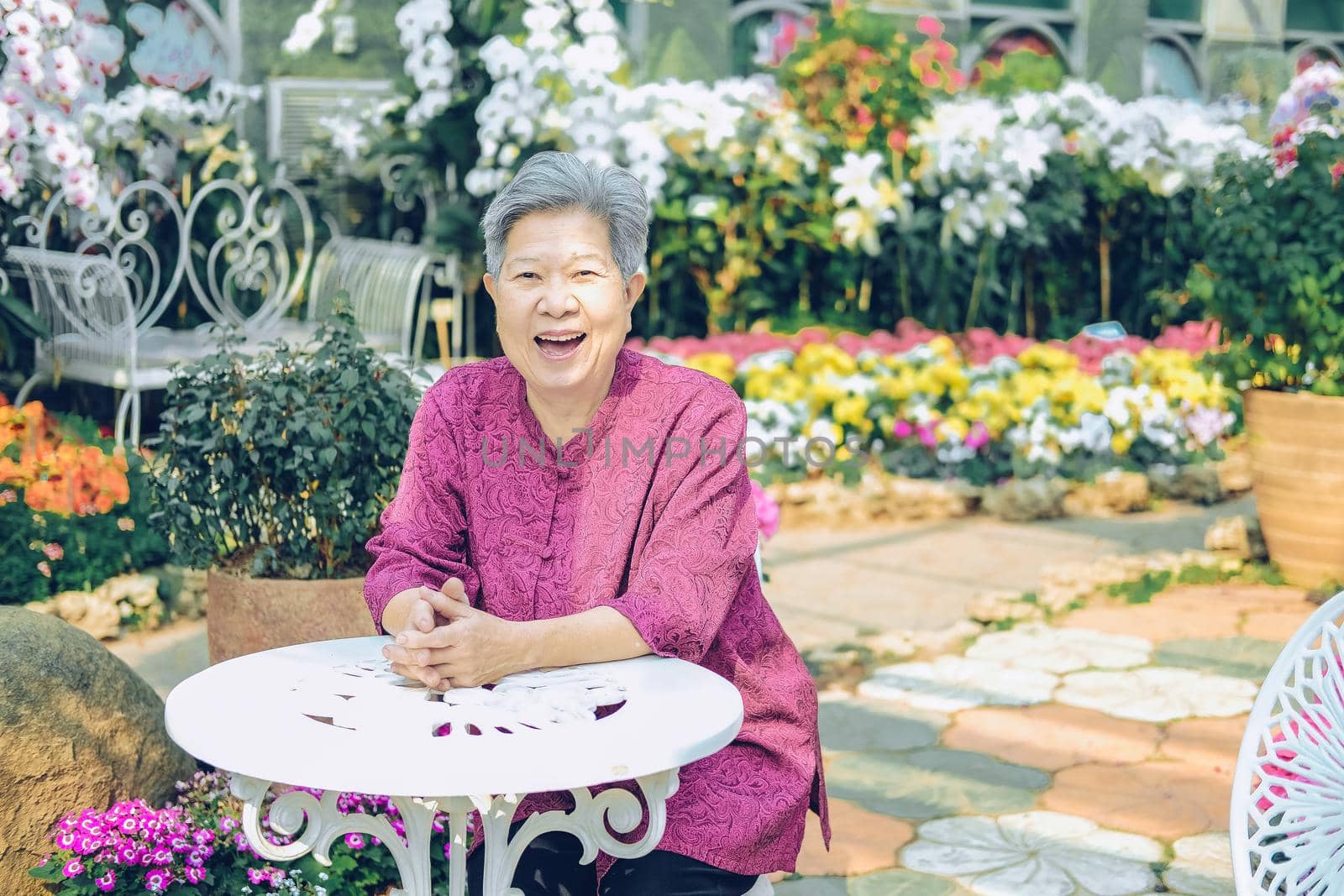 old elder woman resting in flower garden. asian elderly female relaxing in park. senior leisure lifestyle