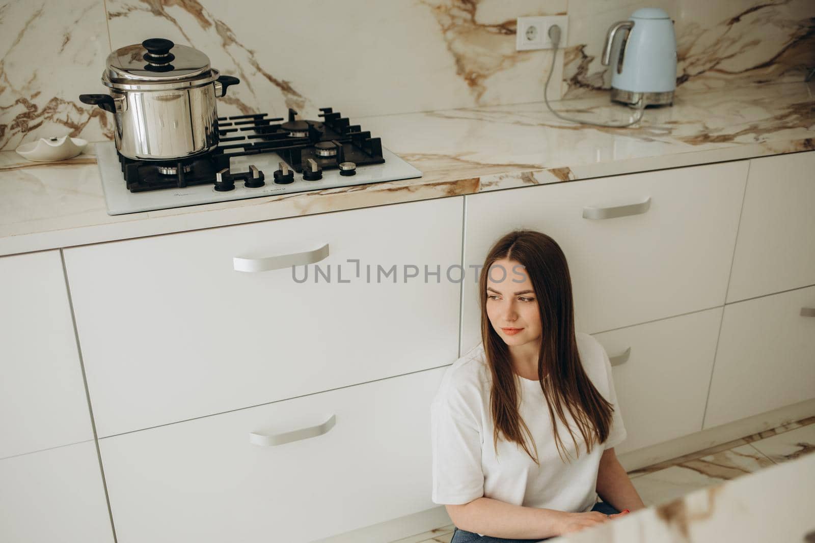Beautiful young woman sitting under the stove waiting for food to be prepared