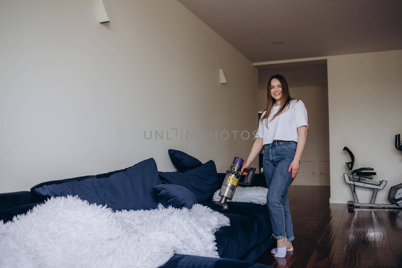 girl cleaning the sofa with a vacuum cleaner..