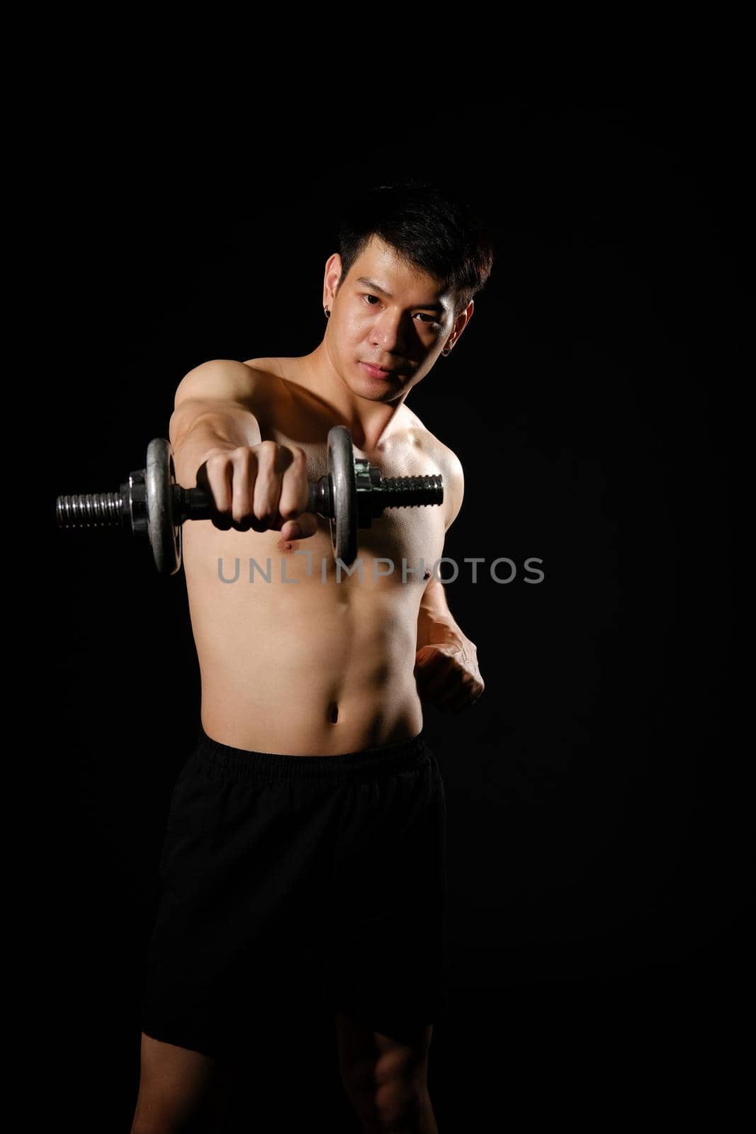 portrait of athletic muscular bodybuilder man with naked torso six pack abs working out with dumbbell. fitness sport exercise concept