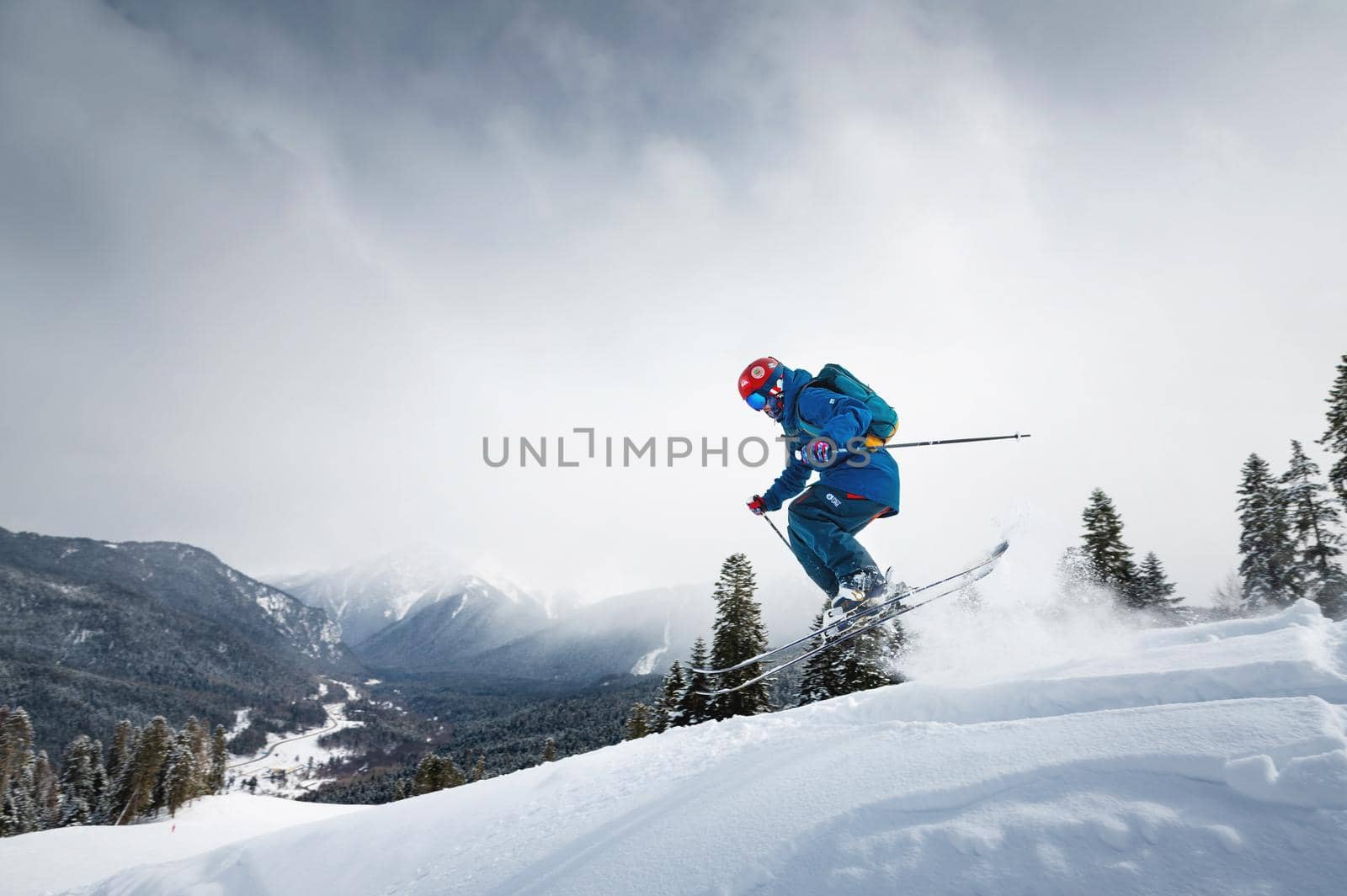 Freeride, a man is stylishly skiing on a snowy slope with snow dust plume behind him.