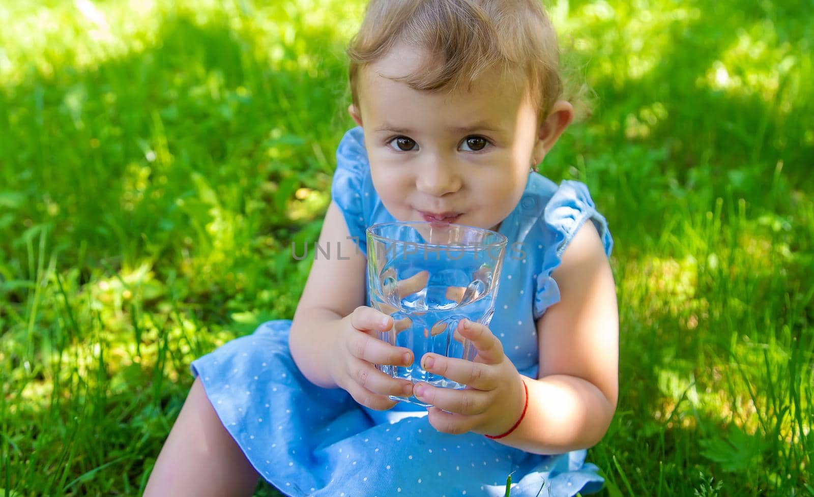 The child drinks water from a glass. Selective focus. by yanadjana