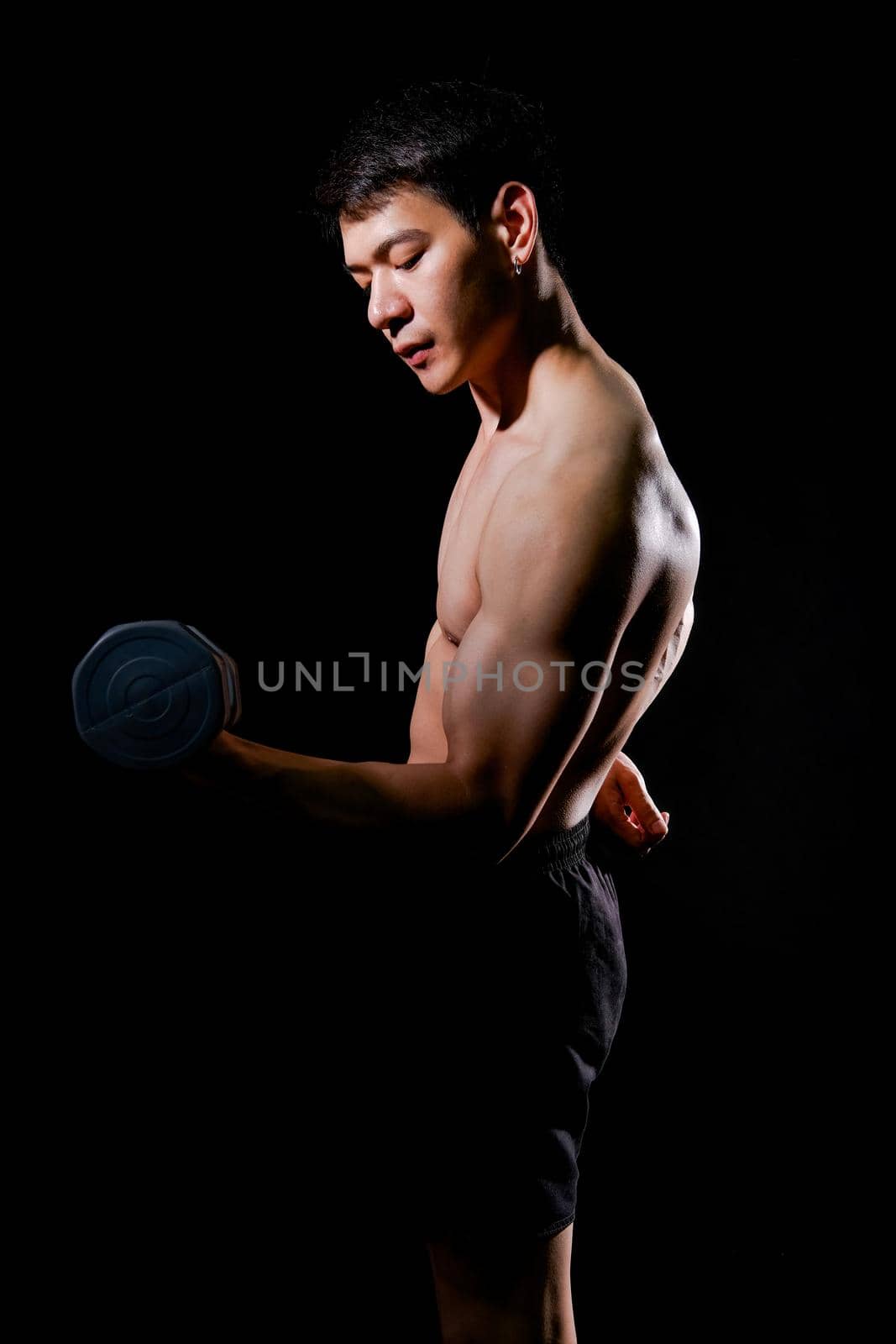 portrait of athletic muscular bodybuilder man with naked torso six pack abs working out with dumbbell. fitness sport exercise concept