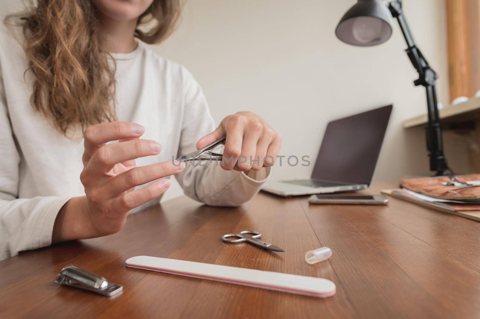 Close-up of hand of caucasian young woman doing manicure at home with nail supplies