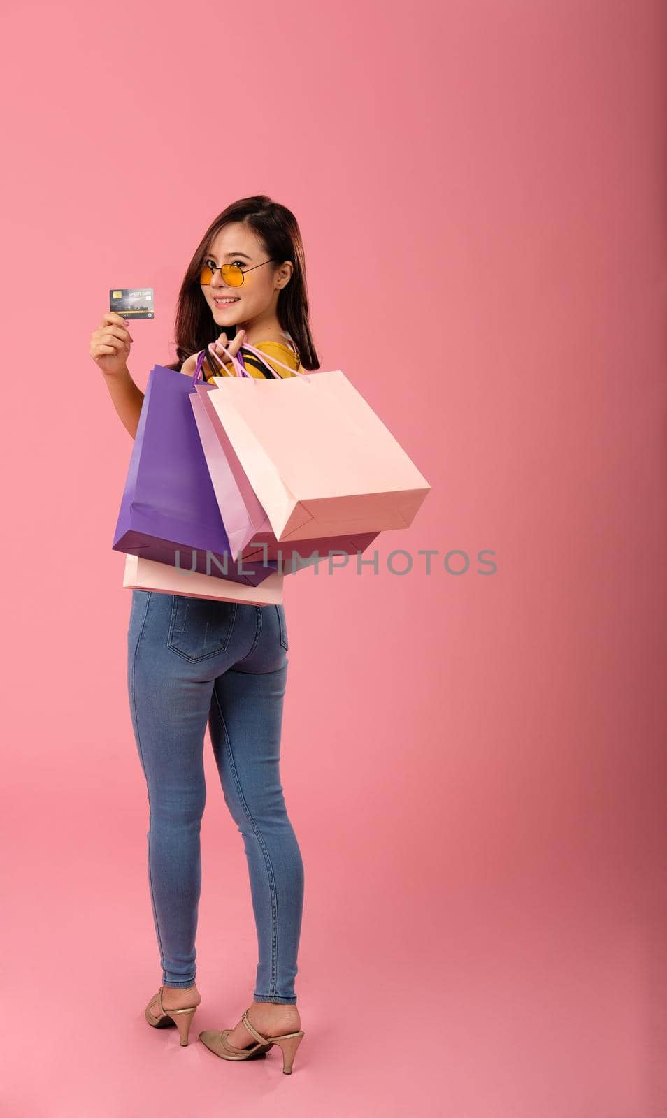 woman holding credit card & shopping bags. consumerism shopaholic lifestyle studio shot